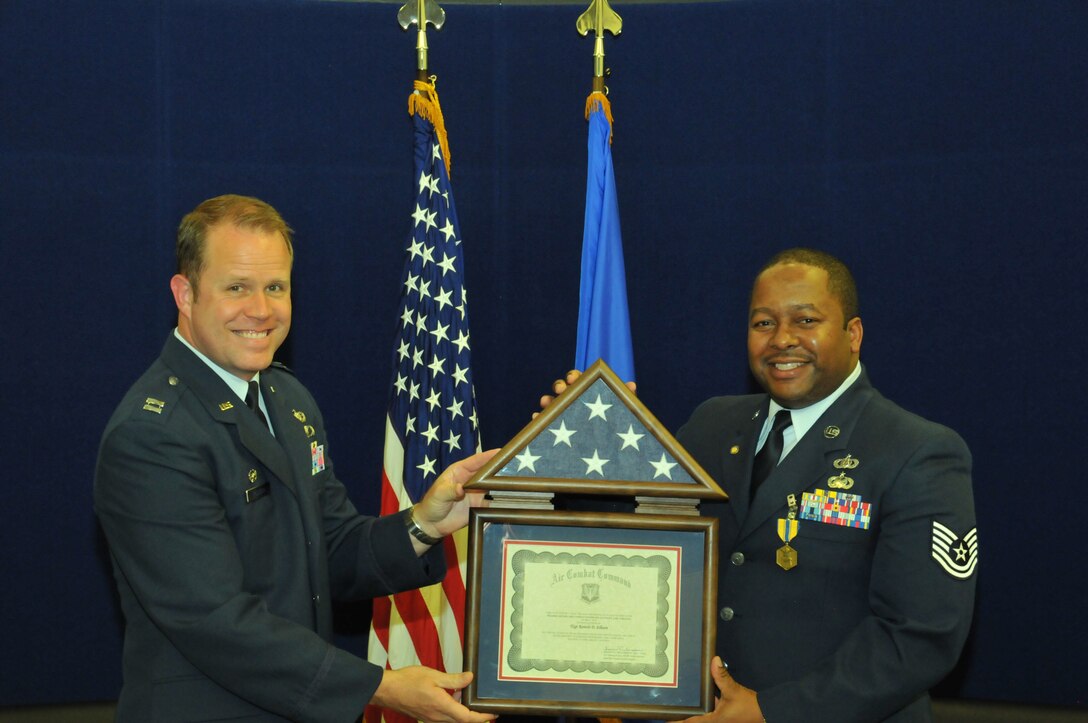 Longtime Band of the Golden West vocalist TSgt Ronicle "Nico" Ellison accepts his shadow box from band commander Capt Jason Plosch during his retirement ceremony, April 18, 2014.
