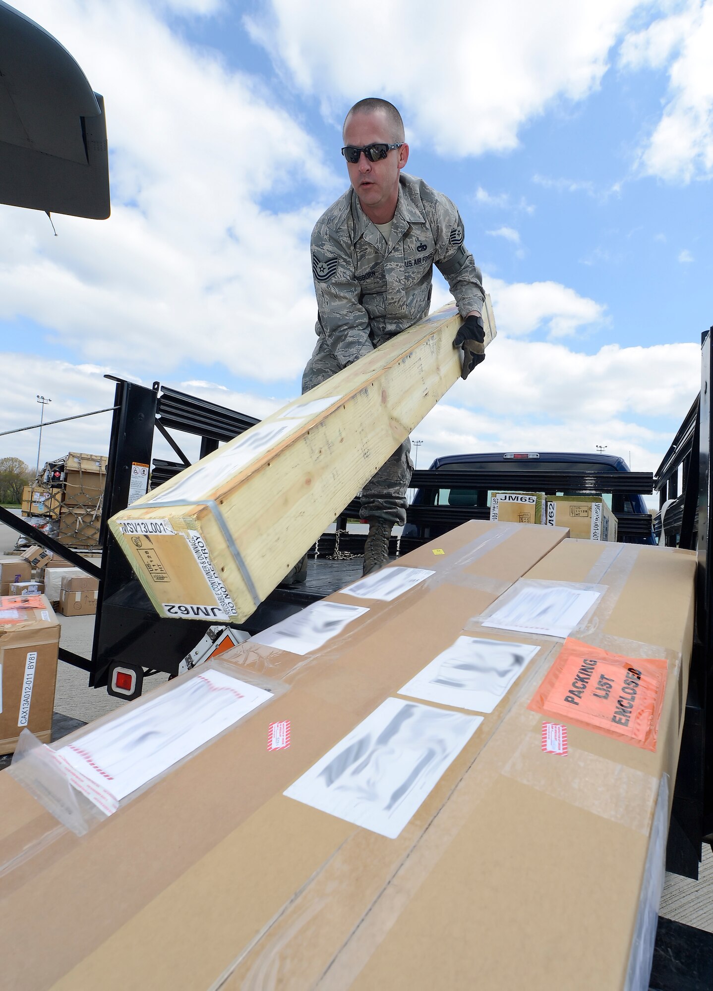 Tech. Sgt. Paul Osborn, 436th Aerial Port Squadron NCO in charge of in-transit munitions section, moves boxes into position for loading on a C-130 Hercules aircraft on April 23, 2014, at Dover Air Force Base, Del. The operation is taking place on the hot cargo ramp at a remote section of the base. Photo illustration/image altered by blurring potentially sensative information on shipping labels prior to publication. (U.S. Air Force photo/Greg L. Davis)