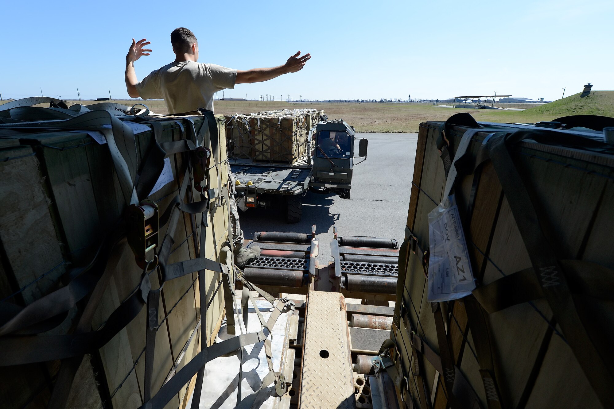 Senior Airman Justin Sims, 436th Aerial Port Squadron in-transit munitions cargo processor, guides a cargo transport vehicle into place as pallets of LUU-2B/B aircraft flares with parachutes are moved to join others in secure storage April 10, 2014, at Dover Air Force Base, Del. The pallets are stored within the warehouse on elevated roller systems which are at the same height of the cargo transport vehicle shown. (U.S. Air Force photo/Greg L. Davis)