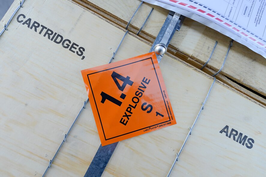 A bright orange sticker is shown affixed to wooden boxes containing small arms cartridges that have just been delivered to the 436th Aerial Port Squadron in-transit munitions section, April 10, 2014, at Dover Air Force Base, Del.  The section processes ammunition and weapons that are transported from Dover. (U.S. Air Force photo/Greg L. Davis)