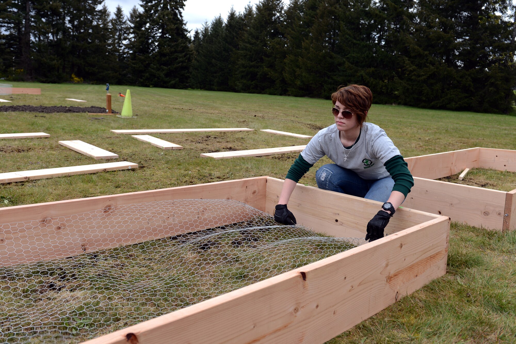 Airman 1st Class Amanda Lewis, 10th Airlift Squadron loadmaster, lays chicken wire in a garden bed April 17, 2014, at Joint Base Lewis-McChord, Wash. To contribute to Earth Day, Airmen volunteered their time to build a community garden by the McChord Field stables. (U.S. Air Force photo/Airman 1st Class Jacob Jimenez)