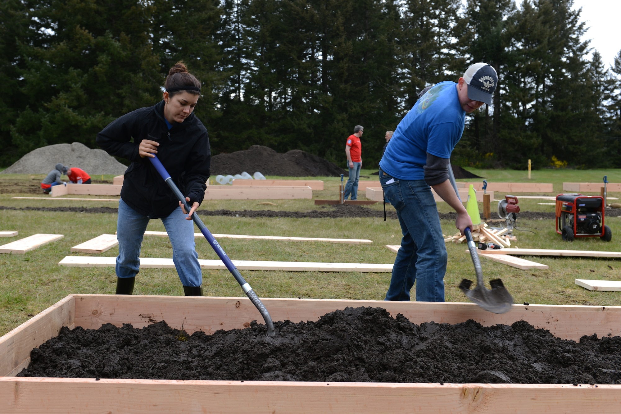 1st Lt. Samantha Caszatt, 7th Airlift Squadron pilot, and Airman 1st Class James Ratzlaff, 62nd Comptroller Squadron customer support technician, mix dirt and compost in a garden bed April 17, 2014, during Earth Week at Joint Base Lewis-McChord, Wash. Airmen teamed up with Sustainable JBLM to build 30 raised garden beds next to the McChord Field stables. (U.S. Air Force photo/Airman 1st Class Jacob Jimenez)