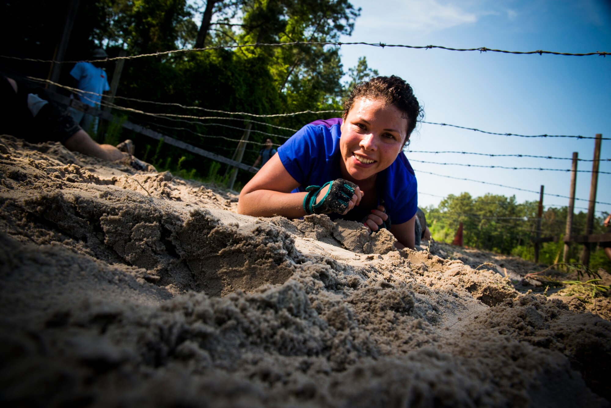 Maria Serran low crawls under barbed wire during the Moody Mudder run April, 26, 2014, in Ray City, Ga. The mud run’s 5K course featured 10 obstacles for participants to conquer. (U.S. Air Force photo by Staff Sgt. Jamal D. Sutter/Released) 