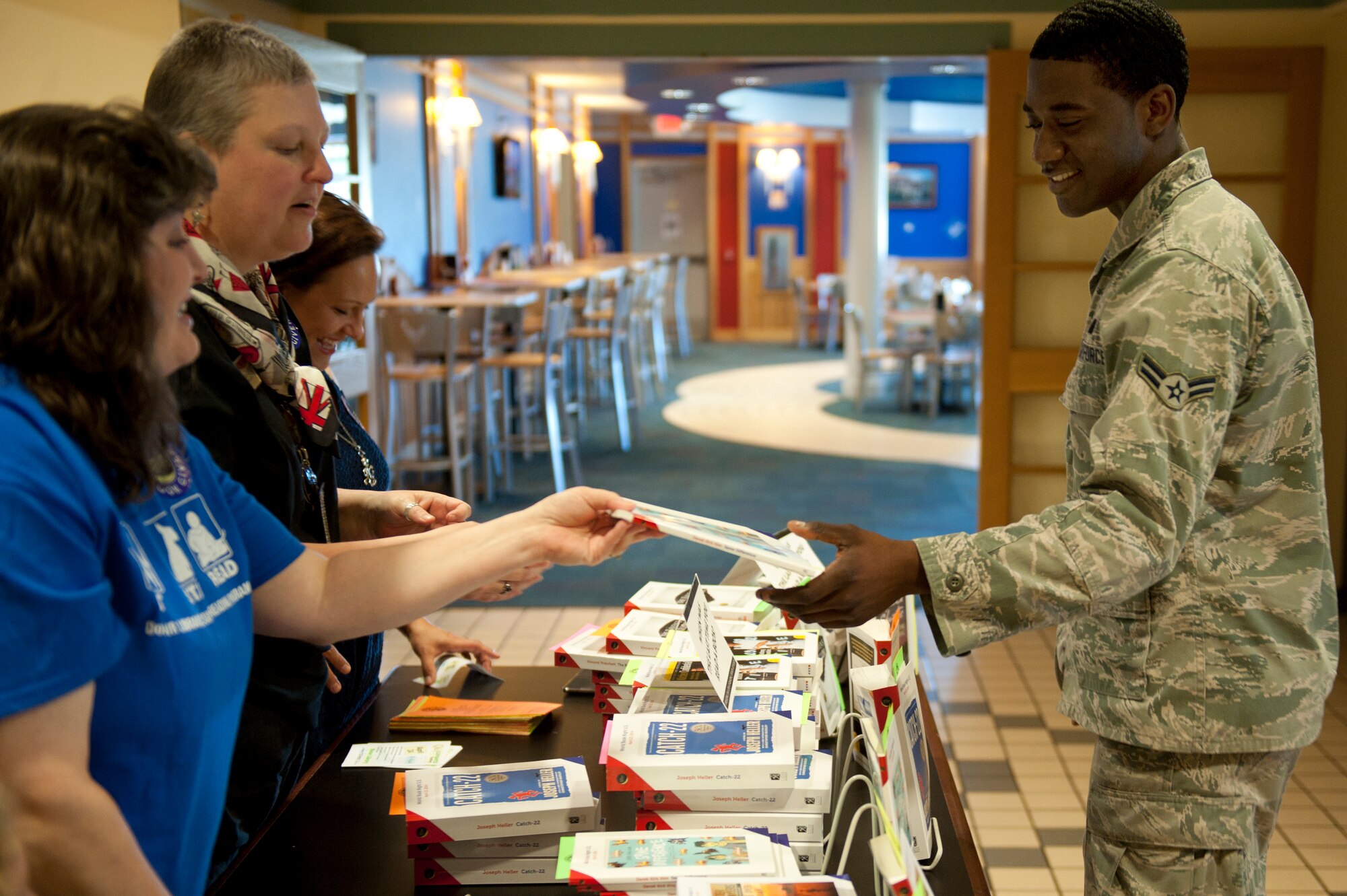 Airman 1st Class Terrence Baker, 4th Logistics Readiness Squadron fuels distribution operator, accepts a free book during World Book Night, April 23, 2014, at the Southern Eagle Dining Facility at Seymour Johnson Air Force Base, N.C. Volunteers gave free books to Airmen in conjunction with the annual event. (U.S. Air Force photo/Airman 1st Class Aaron J. Jenne) 