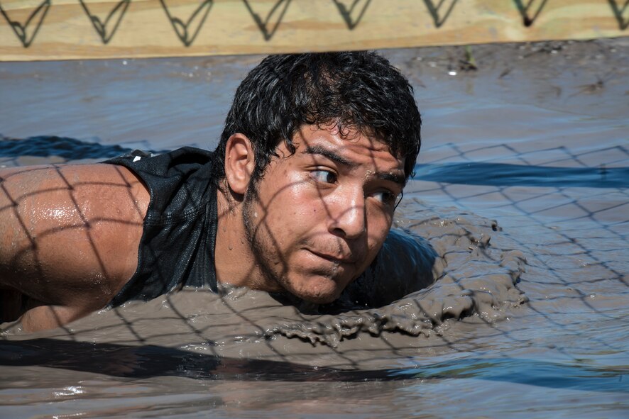 A runner low crawls through a puddle under a fence during a mud-run in Ray City, Ga., April 26, 2014. The inaugural Moody Mudder 5k had more than 500 participants comprised of Moody Airmen and their families as well as members of the local community. Throughout the 3.12 miles, runners had to overcome obstacles such as barbed wire, monkey bars, low crawls, balance beams and climbing walls. (U.S. Air Force photo by Airman 1st Class Ryan Callaghan/Released)