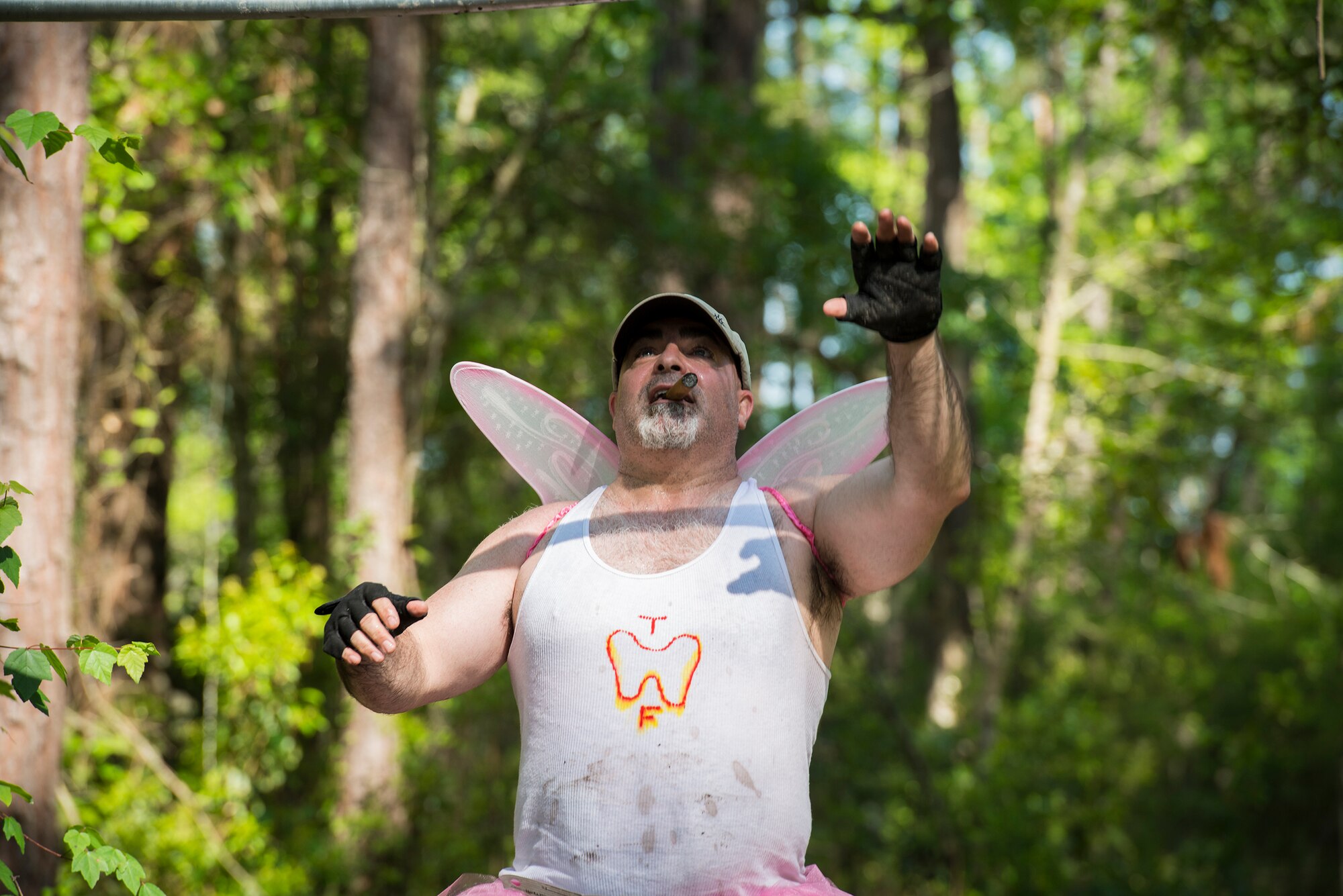 A costumed runner reaches for the first rung on a set of monkey bars while smoking a cigar during a mud-run in Ray City, Ga., April 26, 2014. The inaugural Moody Mudder 5k had more than 500 participants comprised of Moody Airmen and their families as well as members of the local community. Throughout the 3.12 miles, runners had to overcome obstacles such as barbed wire, monkey bars, low crawls, balance beams and climbing walls. (U.S. Air Force photo by Airman 1st Class Ryan Callaghan/Released)