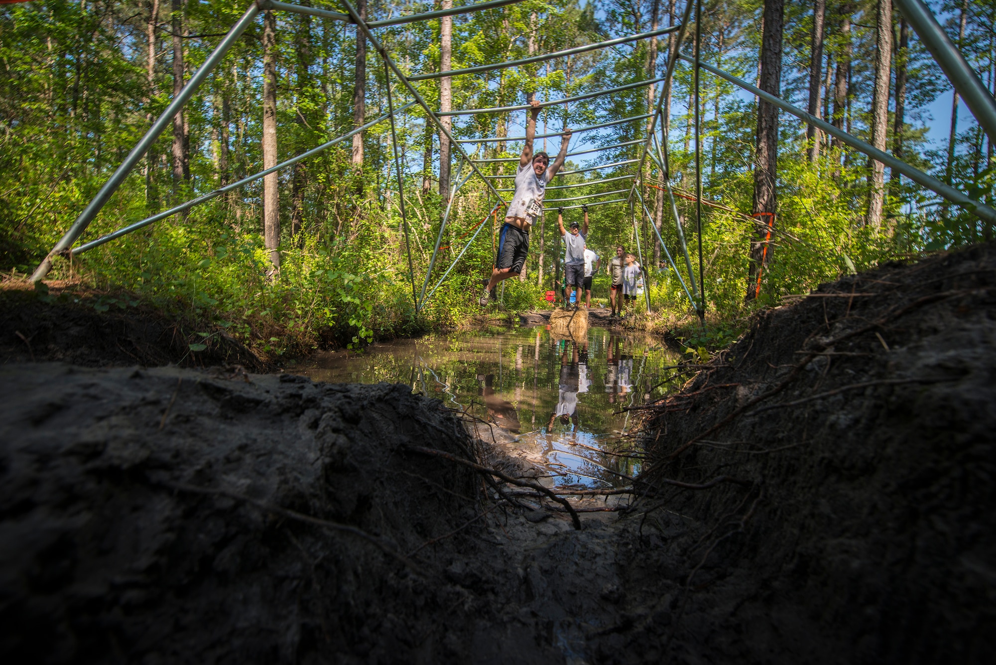 Runners work their way across a set of monkey bars during a mud-run in Ray City, Ga., April 26, 2014. The inaugural Moody Mudder 5k had more than 500 participants comprised of Moody Airmen and their families as well as members of the local community. Throughout the 3.12 miles, runners had to overcome obstacles such as barbed wire, monkey bars, low crawls, balance beams and climbing walls. (U.S. Air Force photo by Airman 1st Class Ryan Callaghan/Released)