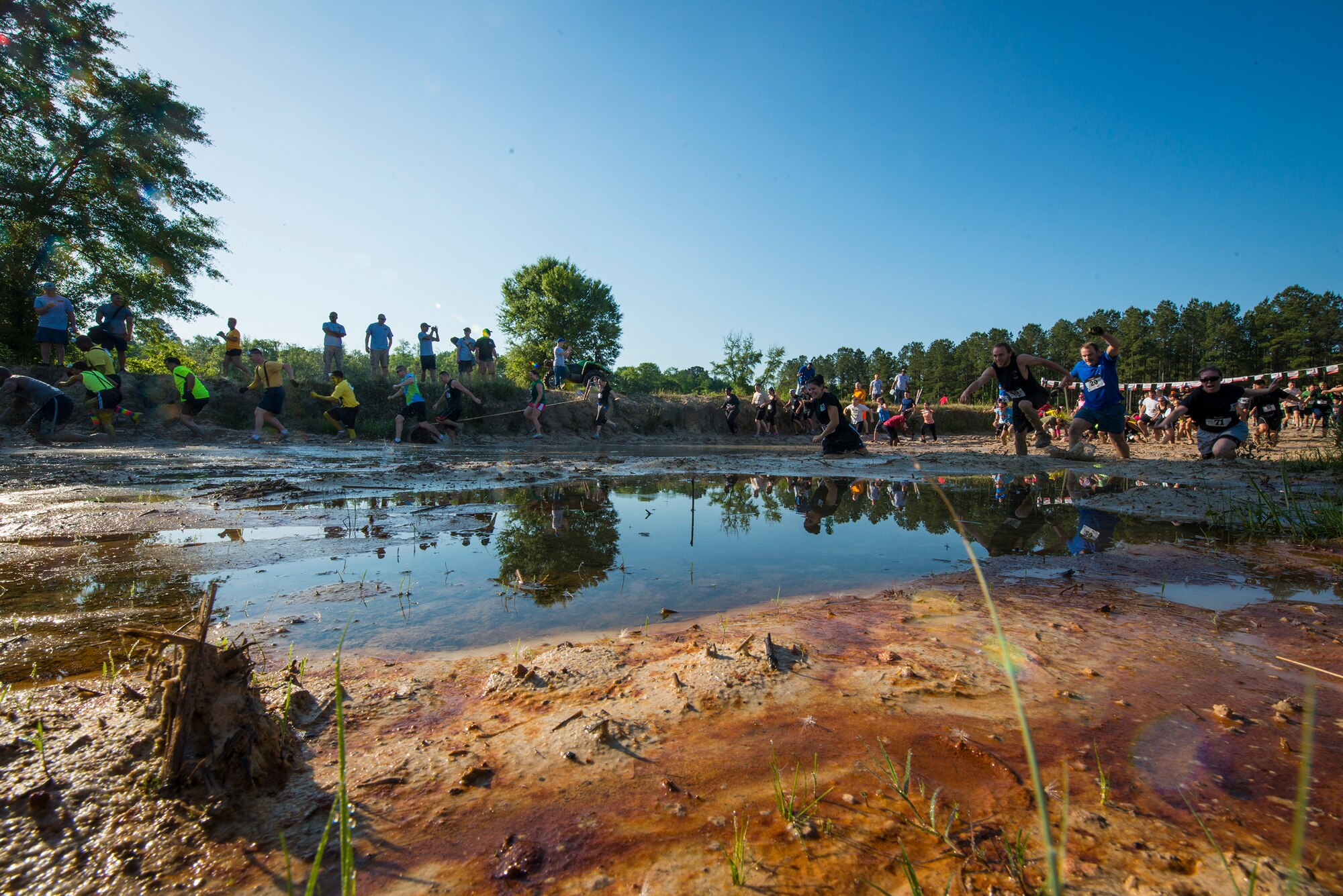 Participants run through a mud pit near the start line of a mud-run in Ray City, Ga., April 26, 2014. The inaugural Moody Mudder 5k had more than 500 participants comprised of Moody Airmen and their families as well as members of the local community. Throughout the 3.12 miles, runners had to overcome obstacles such as barbed wire, monkey bars, low crawls, balance beams and climbing walls. (U.S. Air Force photo by Airman 1st Class Ryan Callaghan/Released)