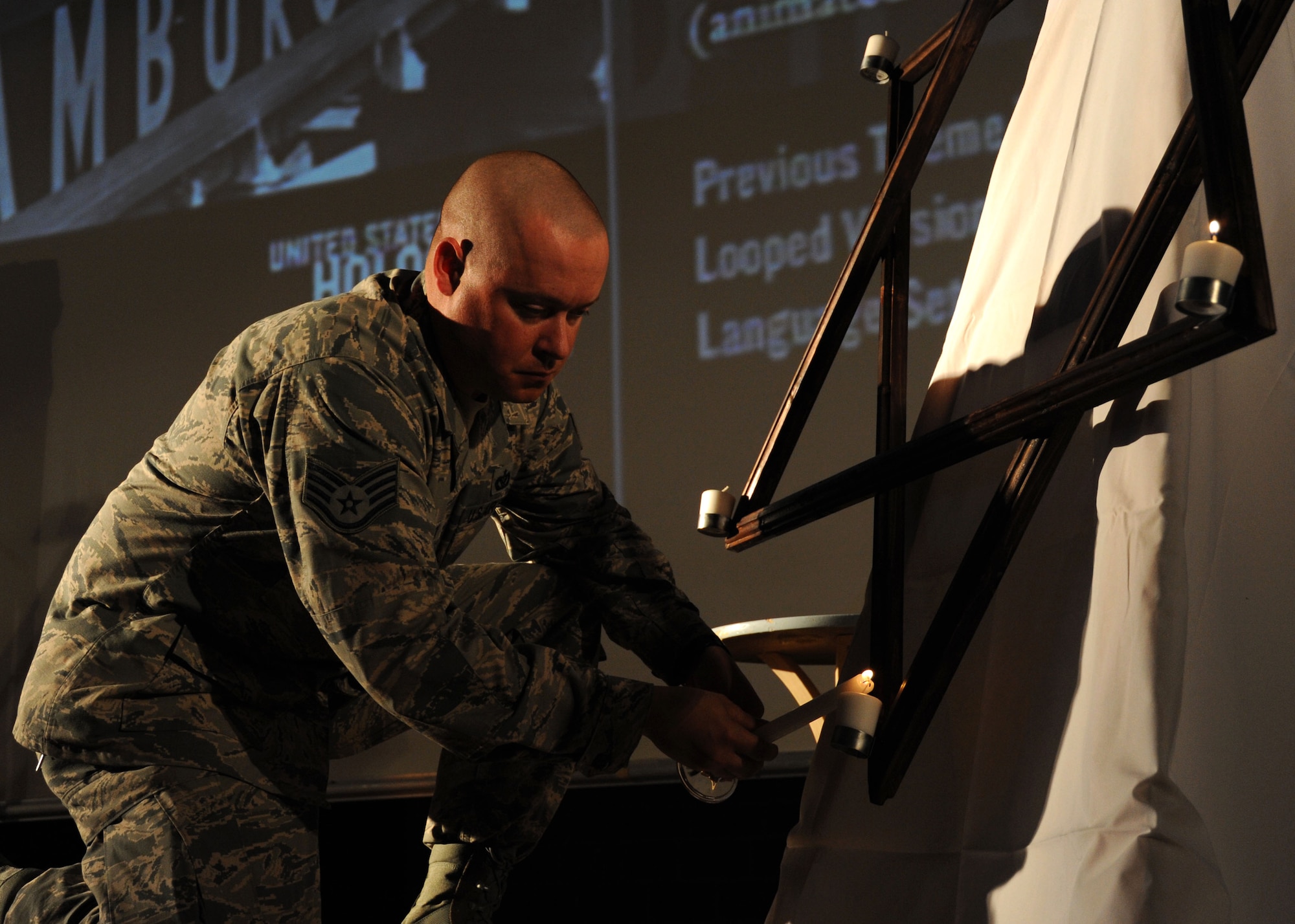 U.S. Air Force Staff Sgt. Christopher Anderson, a 52nd Civil Engineer Squadron water and fuels system maintenance craftsman, lights six candles in remembrance of the six million victims of the Holocaust during a Holocaust Days of Remembrance ceremony April 28, 2014, at Spangdahlem Air Base, Germany.  Ceremony attendees read a name of a person killed as part of the remembrance. (U.S. Air Force photo by Airman 1st Class Dylan Nuckolls/Released)