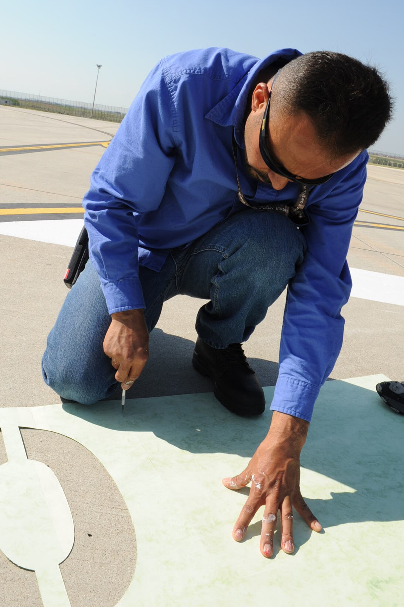 Mustafa Aostu, 39th Civil Engineer Squadron contractor, cuts out a stencil on the flightline April 22, 2014 at Incirlik Air Base, Turkey. Several members of the 39th CES worked together to paint new Controlled Movement Area markings to be more safe and efficient for vehicles and aircraft. (U.S. Air Force photo by Staff Sgt. Eboni Reams/Released)