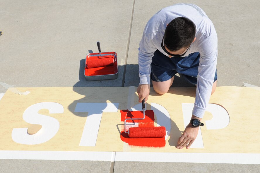 Senior Airman Garcia, 39th Civil Engineer Squadron command support staff, paints a stop sign stencil on the flightline April 22, 2014, Incirlik Air Base, Turkey. Several members from the 39th CES jump started the project to ensure the safety standards for operating vehicles on the flightline. (U.S. Air Force photo by Staff Sgt. Eboni Reams/Released)