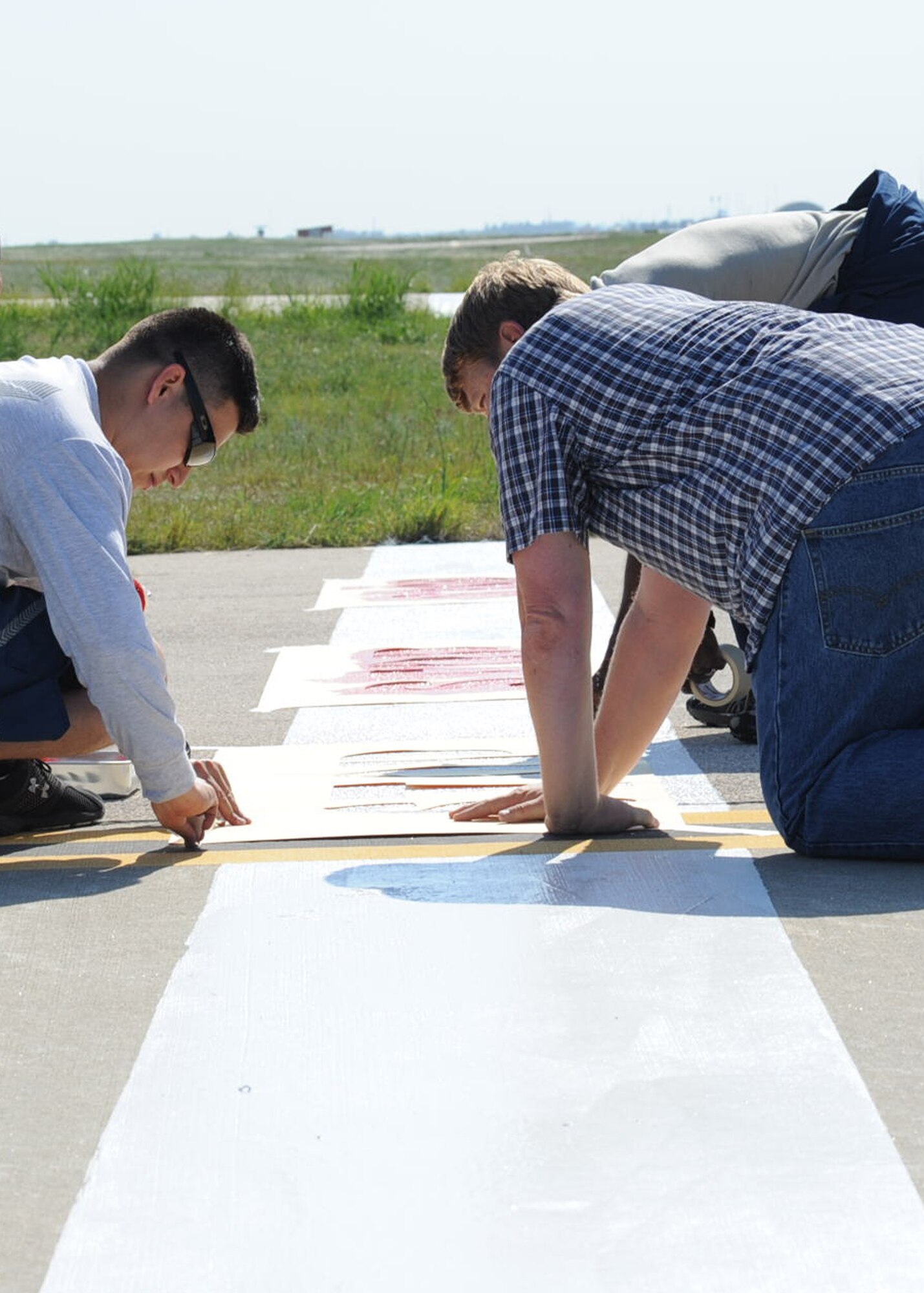 Senior Airman Garcia, 39th Civil Engineer Squadron command support staff, and Charles Sanderson 39th Civil Engineer Squadron facilities manager, tape down a stencil April 22, 2014 at Incirlik Air Base, Turkey. Members planned and executed an in-house project to improve the safety on the flightline. (U.S. Air Force photo by Staff Sgt. Eboni Reams/Released)