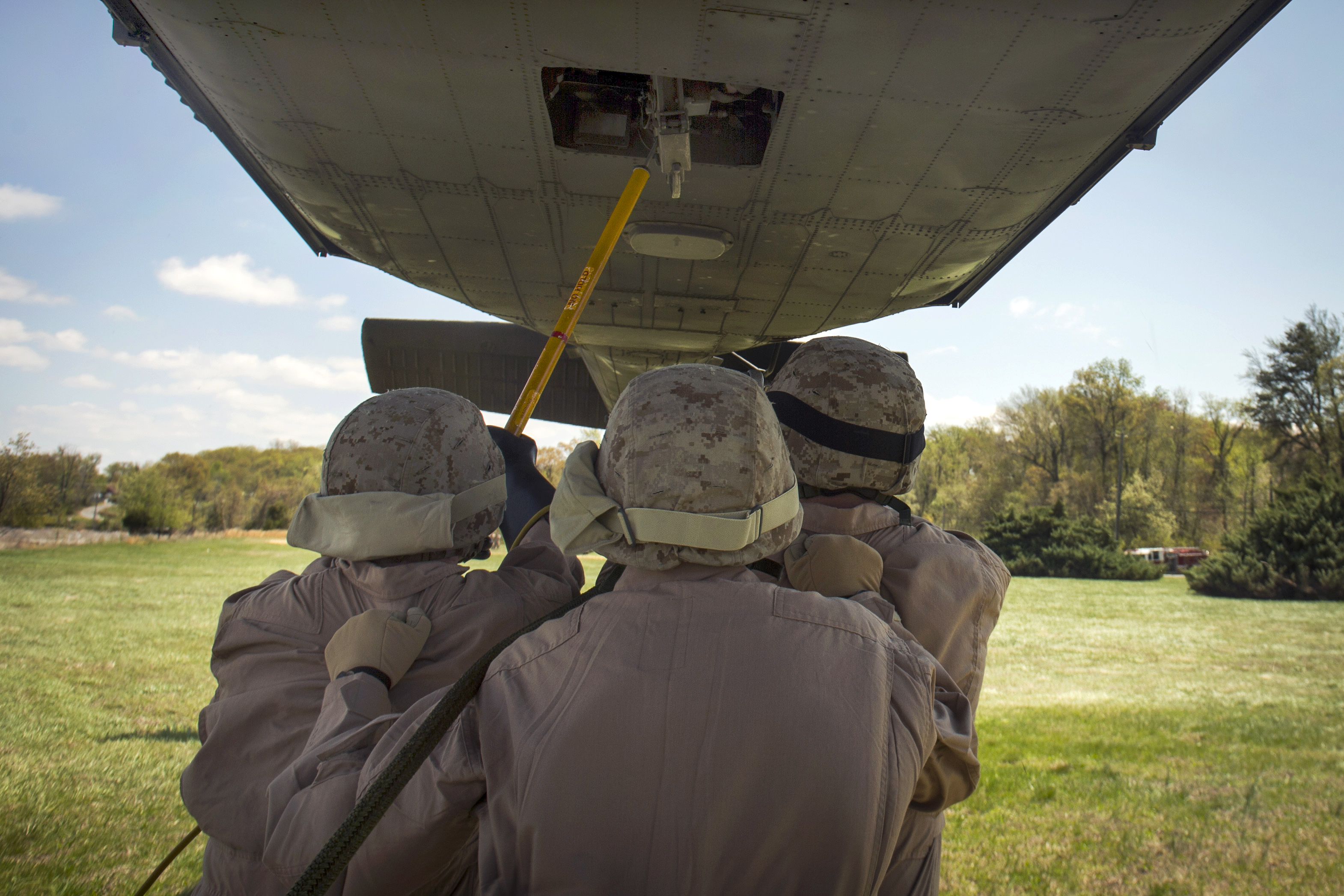 Marines hook cargo under an Army UH60 Black Hawk helicopter during slingload training on Naval
