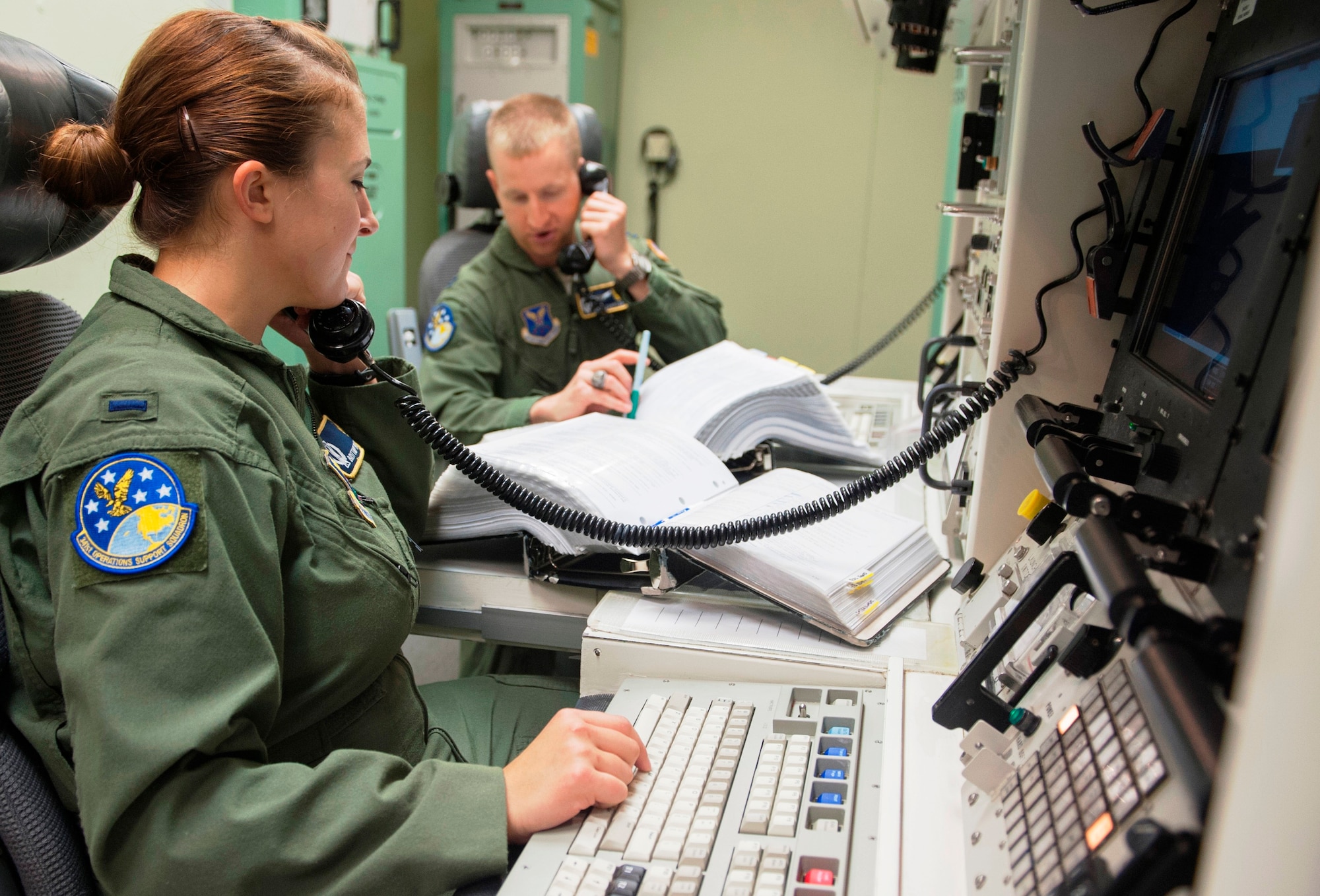 First Lt. Brittany Morton, left, and her missileer partner answer their phones during a trainer ride at the missile procedures trainer. Two missileers man a launch control center together and take turns sleeping so that one person is watching the LFs at all times. Morton is a 490th Missile Squadron missile combat crew commander. (U.S. Air Force photo/Beau Wade)