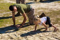 Cpl. Justin Glass, an automotive maintenance technician with 2nd Maintenance Battalion, Combat Logistics Regiment 25, 2nd Marine Logistics Group, helps a child through a modified combat fitness test during an open house aboard Camp Lejeune, N.C., April 24, 2014. The open house gave family members the opportunity to visit and catch a glimpse of the life of Marines in the battalion while taking part in some of the Marines’ day-to-day activities.