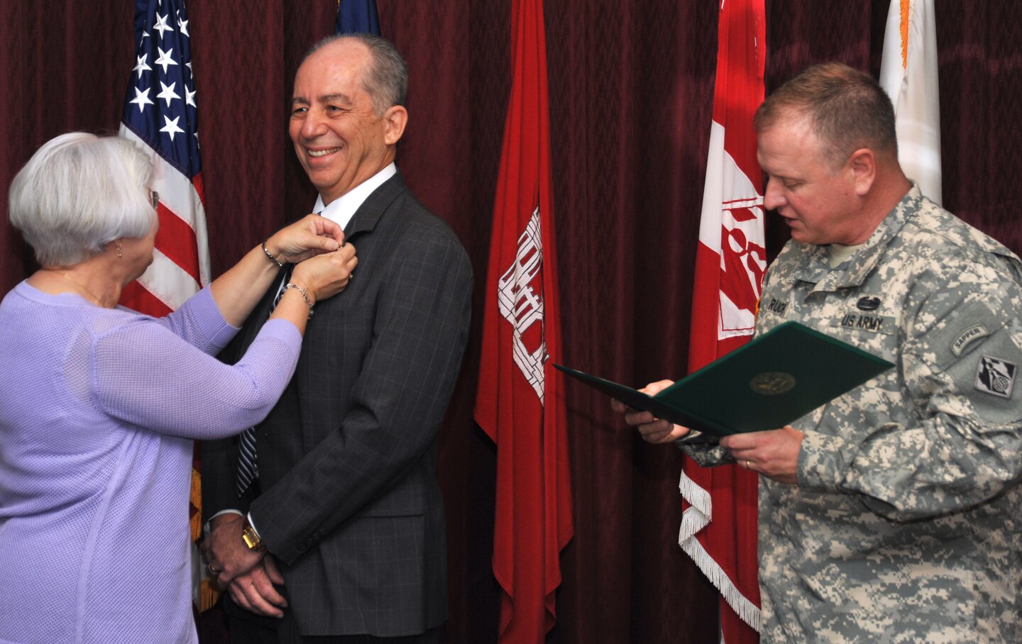 Nancy Schuler pins on husband Ralph's retirement pin as Huntsville Center Commander Col. Robert Ruch reads the certificate April 25 in the center's command conference room.