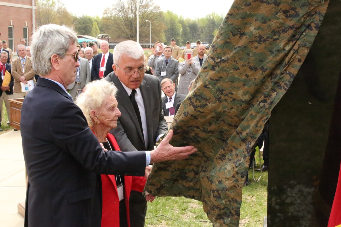 Two men help Nell Hannah, mother of a deceased Marine officer, unveil the 6-67 Memorial dedication at The Basic School on April 25, 2014. The memorial was dedicated to the class who suffered 50 casualties and more than 200 wounded Marines. 