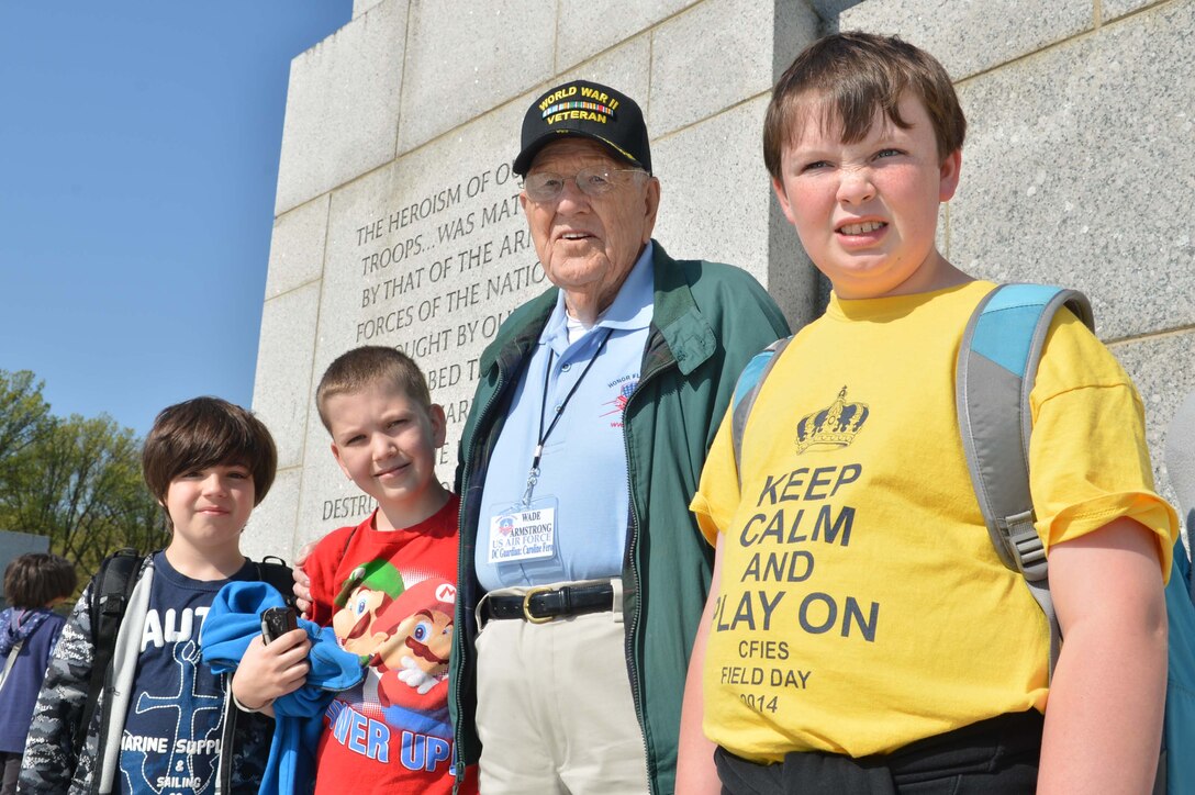 Retired Army Air Corps Sgt. Wade H. Armstrong, World War II veteran, takes multiple photos with children and families during an Austin, Texas, Honor Flight event at the World War II Memorial in Washington, D.C., on April 26, 2014. (Marine Corps Photo by Cpl. Antwaun Jefferson)
