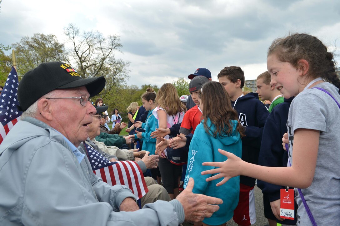 Retired Army Air Corps Sgt. James White, World War II veteran, and his fellow veterans shake hands with children who thanked them for their service during an Austin, Texas, Honor Flight event at the Marine Corps War Memorial in Arlington, Va., on  April 26, 2014. At every monument the veterans visited, people lined up to thank them for their service. (Marine Corps Photo by Cpl. Antwaun Jefferson)