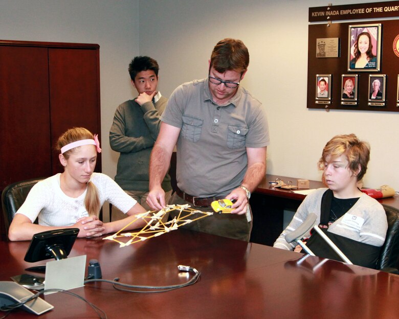 Catherine Guilhur and Willow Eichler watch as Corps intern AJ Moore tests the spaghetti bridge constructed by Guilhur and Eichler as one of the design challenges during the 21st Annual Take Our Daughters And Sons To Work® program held at the district offices in Los Angeles April 24. Nearly two dozen children of U.S. Army Corps of Engineers Los Angeles District employees participated in the event.