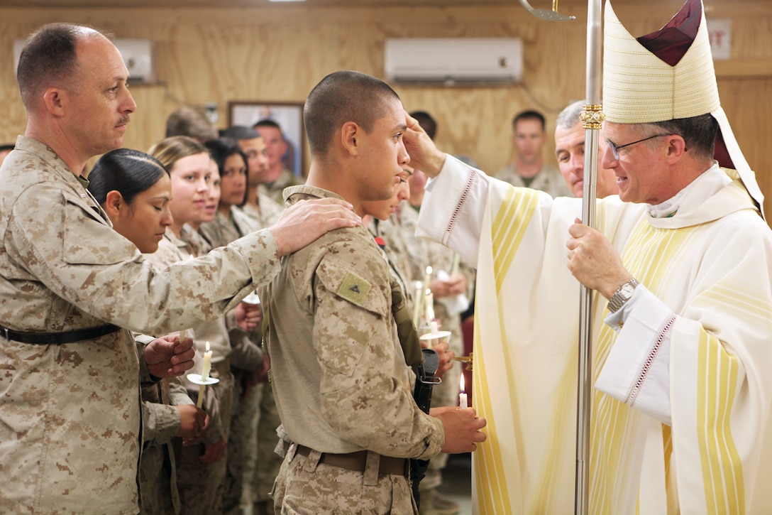Archbishop Timothy P. Broglio, right, who leads the Roman Catholic Archdiocese for the military services, confirms service members into the Catholic faith aboard Camp Leatherneck, Helmand province, Afghanistan, April 19, 2014. Archbishop Broglio baptized and confirmed several service members and took the time to take individual and group photos with them. (U.S. Marine Corps photo by Cpl. Joshua Young)