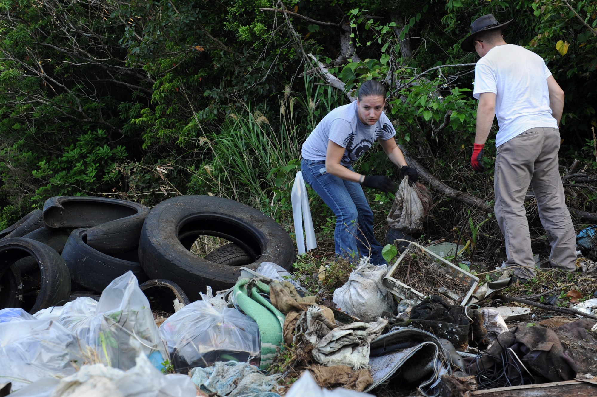 U.S. Air Force Staff Sgt. Genevieve Mancino, 353rd Special Operations Squadron aircrew flight equipment craftsman, and Staff Sgt. Kolton Gomez, 18th Equipment Maintenance Squadron aerospace ground equipment craftsman, gather garbage during a jungle cleanup in Yomitan, Okinawa, Japan, April 18, 2014.  Approximately 80 volunteers from Kadena Air Base participated in the 718th Civil Engineer Squadron-sponsored cleanup which took place outside the gate of Kadena’s munitions area.  (U.S. Air Force photo by Airman 1st Class Zade C. Vadnais)