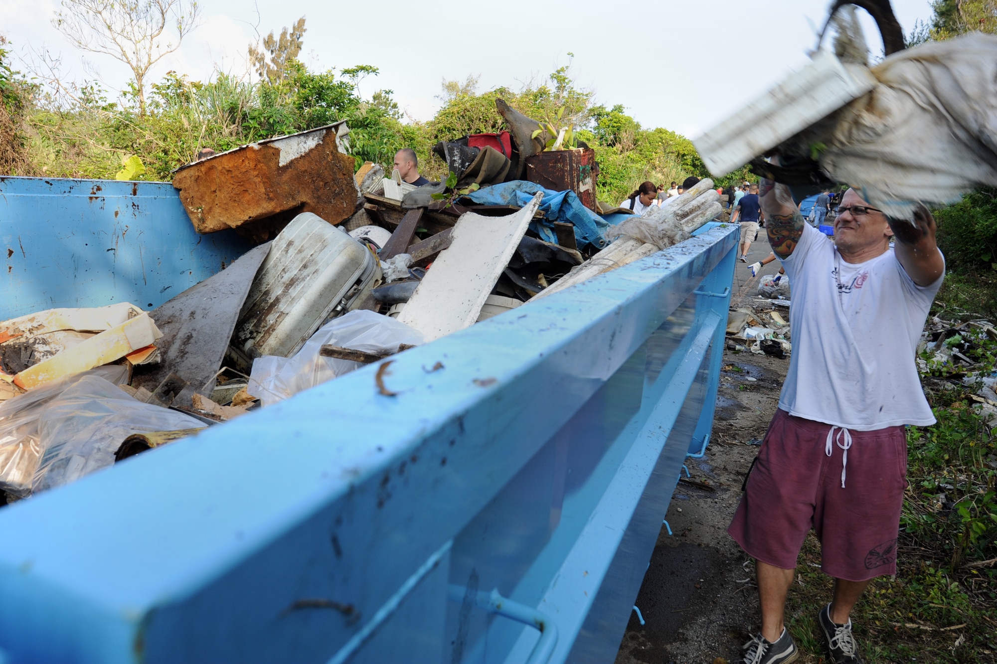 U.S. Air Force Senior Master Sgt. Scott Etler, 18th Wing Command Post superintendent, tosses garbage into a dumpster during a jungle cleanup in Yomitan, Okinawa, Japan, April 18, 2014.  The annual clean-up, which was sponsored by the 718th Civil Engineer Squadron, had approximately 80 volunteers from Kadena Air Base gather to fill six dumpsters with garbage from a small stretch of jungle just outside of Kadena’s munitions area.  (U.S. Air Force photo by Airman 1st Class Zade C. Vadnais)