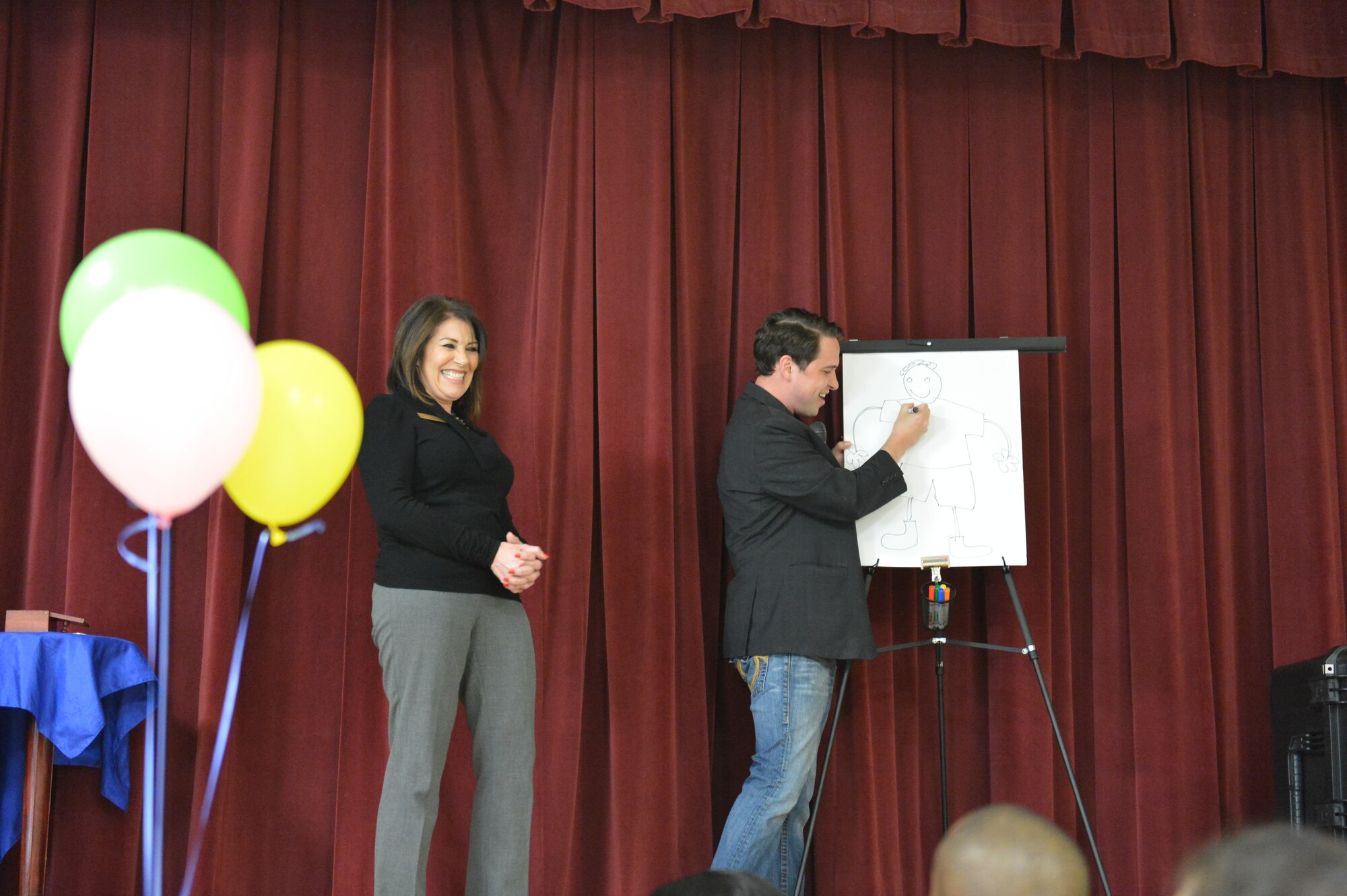 Nate Jester, the Ace of Illusions, and Vicky Nelson, Harborstone Credit Union business sales and services manager perform a magic trick 28 April, 2014, for families and children at the Deployed Family Dinner at Joint Base Lewis-McChord, Wash. Nelson and other civic leaders donated toys, movies, gift cards and a boat cruise to families with deployed members. (U.S. Air Force photo/Staff Sgt. Russ Jackson)