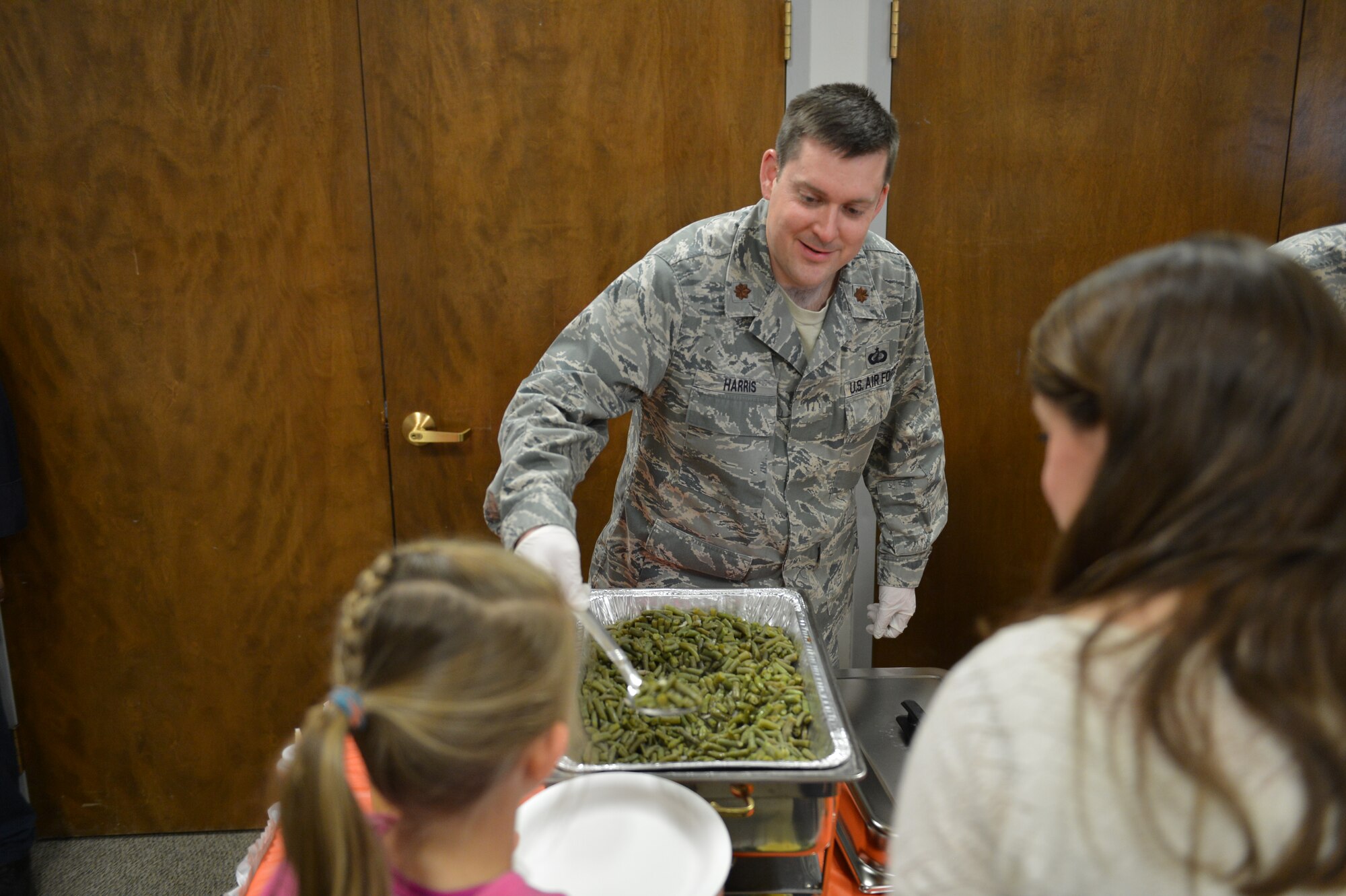 Maj. Neil Harris, 62nd Comptroller Squadron commander, serves green beans 28 April 2014, to families attending the Deployed Family Dinner at Joint Base Lewis-McChord, Wash. Harris, along with other squadron commanders and first sergeants, showed their support to families with deployed members by serving them a hot cooked meal free of charge. (U.S. Air Force photo/Staff Sgt. Russ Jackson)