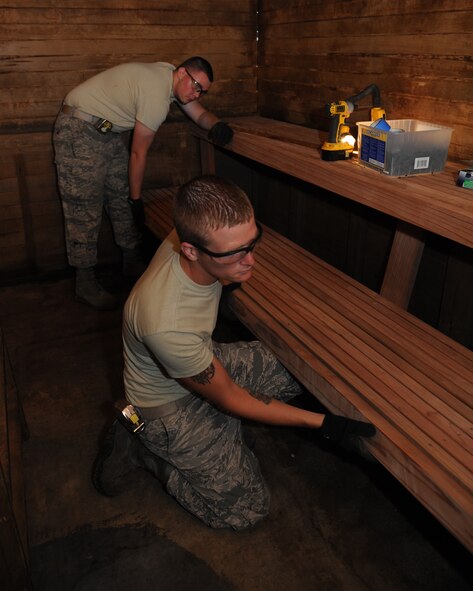 Staff Sgt. Cody Wiley, front, and Airman 1st Class Clarence Archibald, 2nd Civil Engineer Squadron Structures section, hold a bench in place so it can be properly anchored to a wall at the Senior Airman Bryan R. Bell Fitness Center on Barksdale Air Force Base, La., April 29, 2014. Structures Airmen were repairing a sauna in the gym to make it more accommodating for base personnel. (U.S. Air Force photo/Senior Airman Benjamin Gonsier)