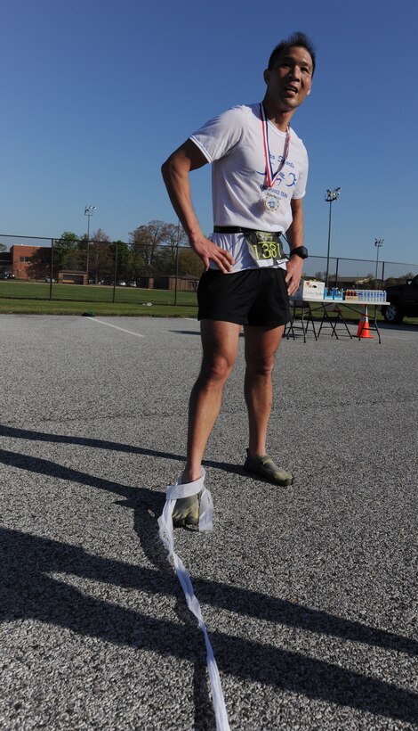 Nick Wong, Joint Base Andrew’s Half Marathon third place finisher, rests at the finish line with a streamer still caught on his foot on April 26, 2014. (U.S. Air Force photo/Senior Airman Nesha Humes)

