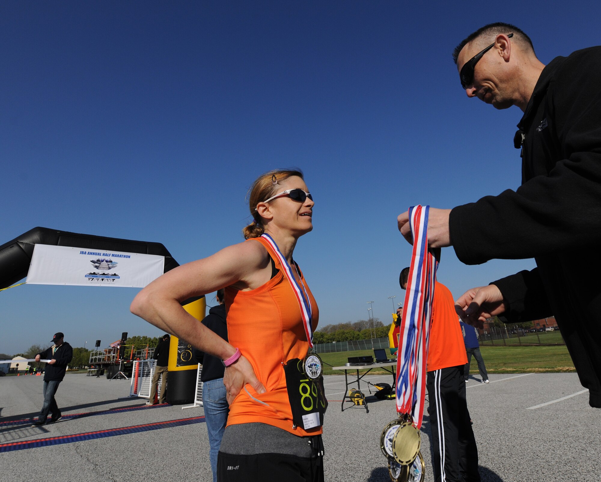 Chief Warrant Officer 4 Deanna Merriman, Defense Intelligent Agency Joint Military Attaché School instructor, receives a medal moments after crossing the finish line. She earned first place for the female runner during the Joint Base Andrews Half Marathon here April 26, 2014. Merriman, an avid runner, participated in her first Boston Marathon just five days prior to competing in Saturday’s race. (U.S. Air Force photo/Senior Airman Nesha Humes)

