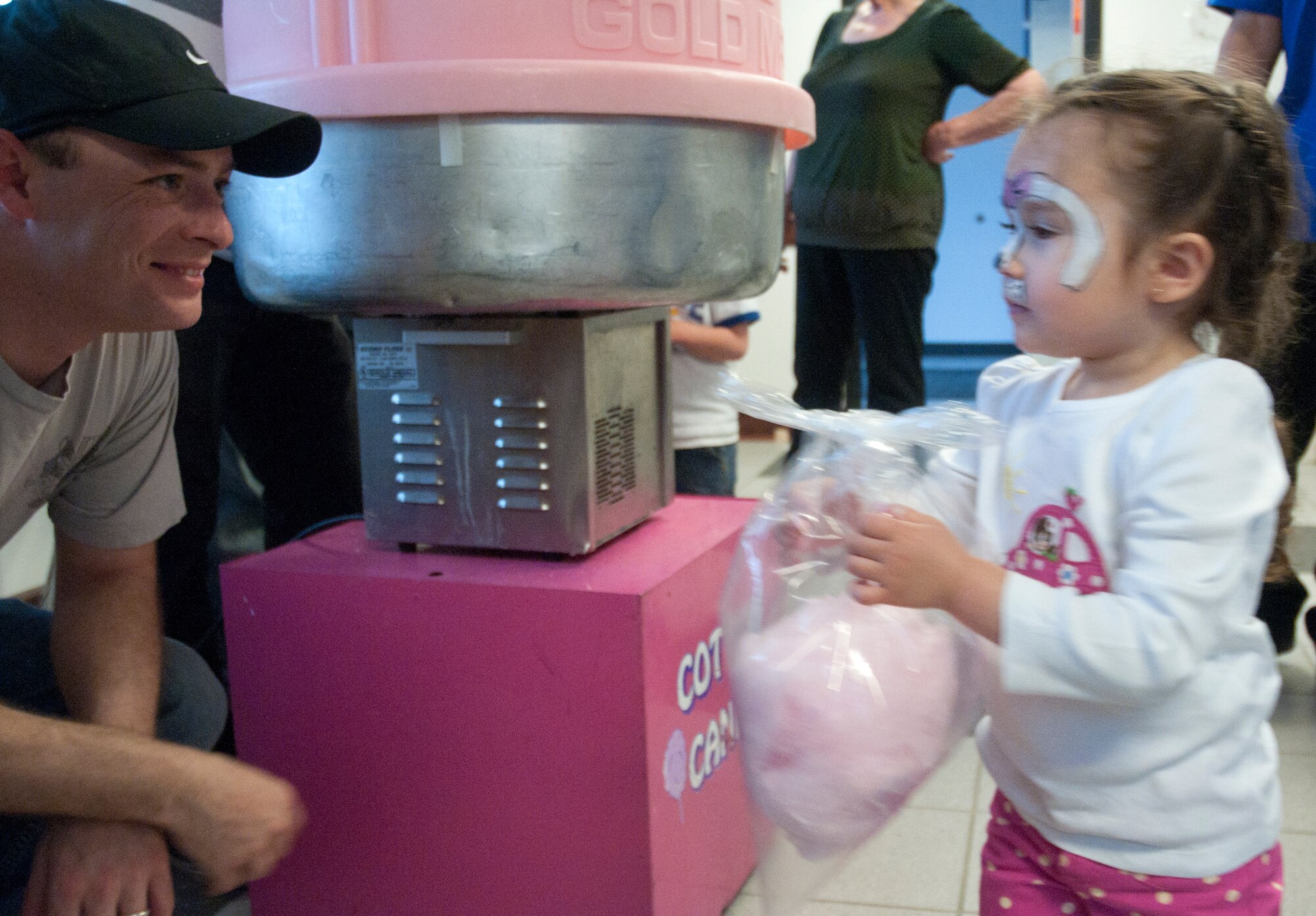Senior Airman Gary Vincent, 90th Medical Operations Squadron, gives a bag cotton candy to Sofia Ramirez, 3, daughter of Master Sgt. Carlos Ramirez, 90th MOS April 25 in the Fall Hall Community Center. Hot dogs, candy apples, cotton candy and other goodies were provided for the families attending the bash. (U.S. Air Force photo by Airman Malcolm Mayfield)