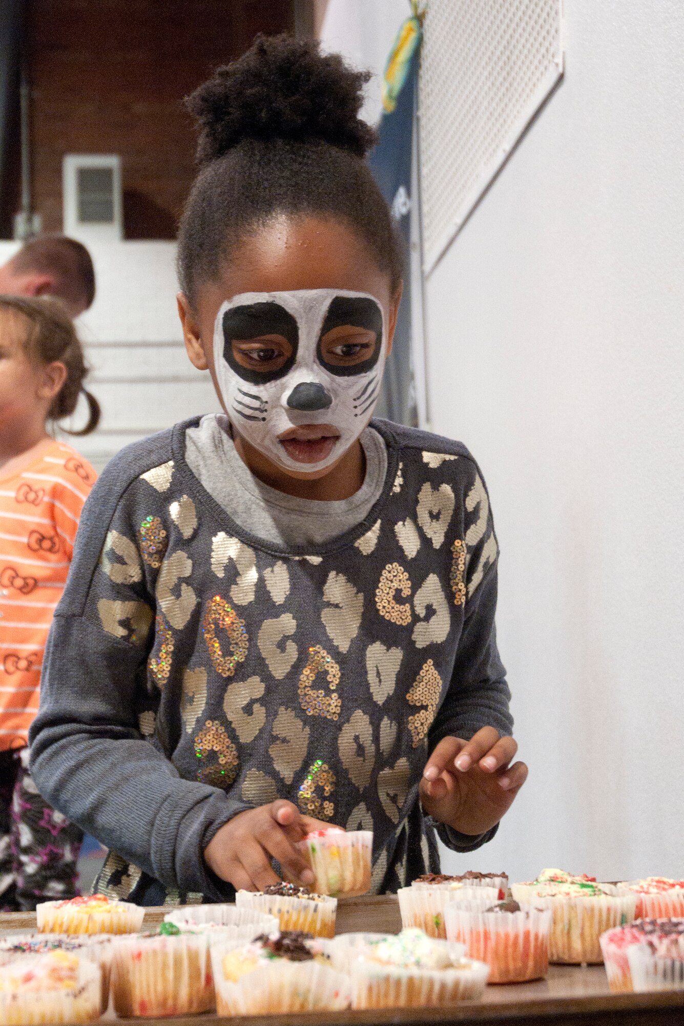 Rebekah Wilson, 8, daughter of Maj. Stephanie Wilson, 90th Munitions Squadron commander, takes a cup cake after winning a game of cake walk April 25 in the Fall Hall Community Center. (U.S. Air Force photo by Airman Malcolm Mayfield)