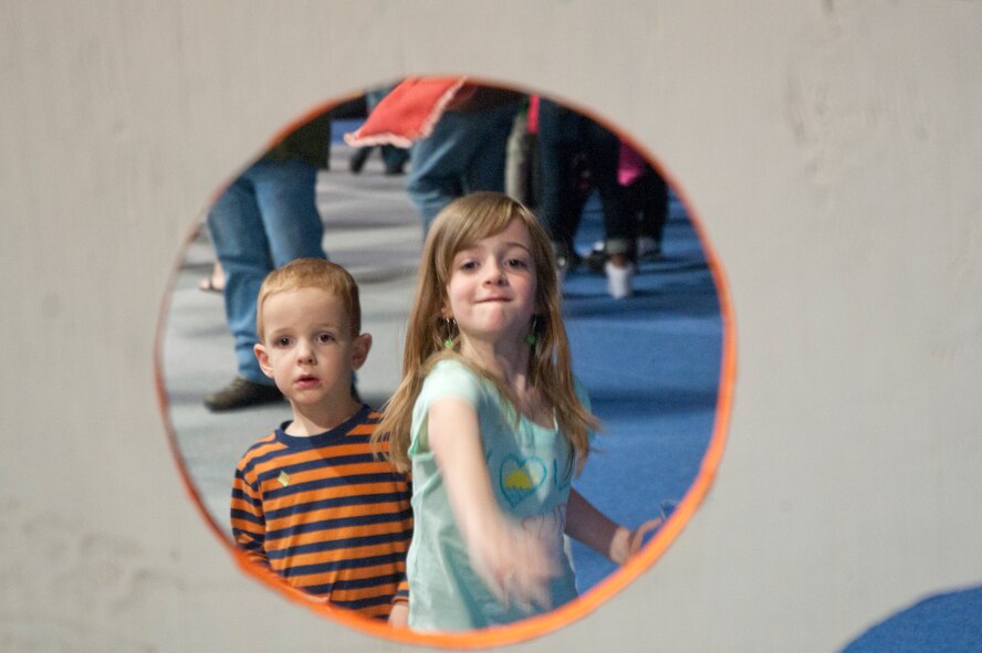 Rythan Layton, 3, watches his sister Harley Layton, 7, throw a bean bag towards a goal April 25 in the Fall Hall Community Center. Both are the children of Staff Sgt. Brandon Layton, 620th Ground Combat Training Squadron. (U.S. Air Force photo by Airman Malcolm Mayfield)