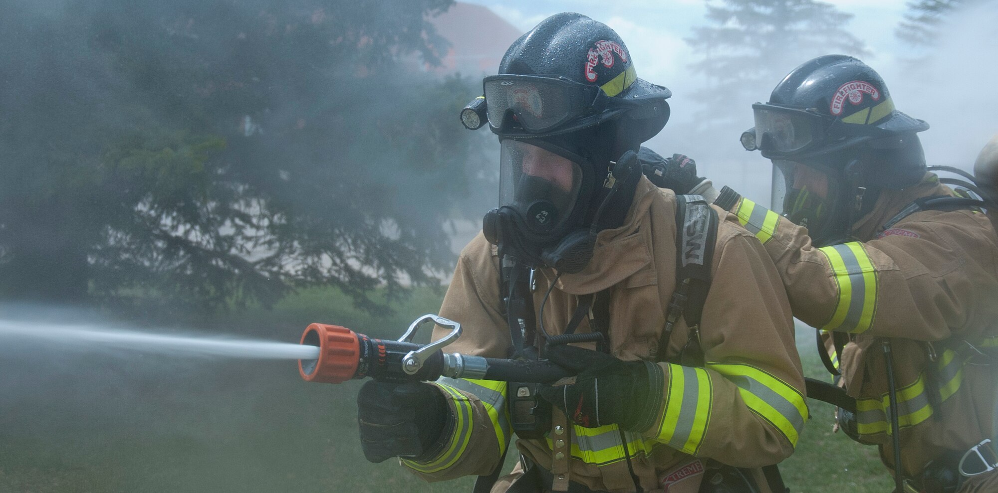 140428-F-GZ967-011 Senior Airman James Vance III and Airman Mike Mikesell, 90th Civil Engineer Squadron firefighters, demonstrate the proper way to combat a fire with the fire hose April 28 in front of the fire house. The pair works together in unison to achieve the proper form necessary to withstand the force of the water pressure. (U.S. Air Force photo by Airman 1st Class Brandon Valle)