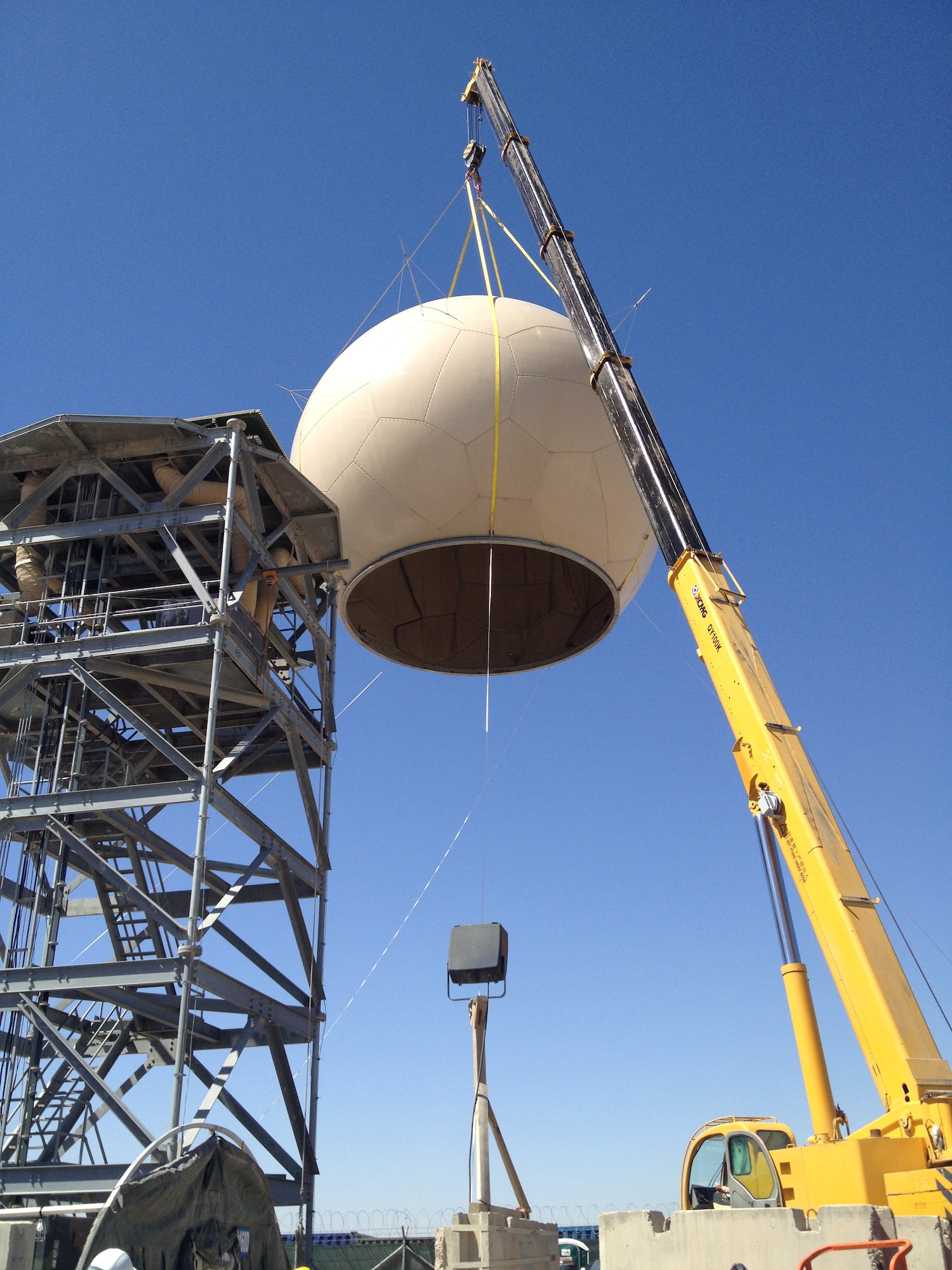 A 100-ft crane removes the 73rd Expeditionary Air Control Squadron's
5000-lb radome from its tower. The aged TPS-75 Radar #1057 sits folded on
top of the tower, ready to be replaced by a refurbished antenna. (Courtesy
photo/Released)
