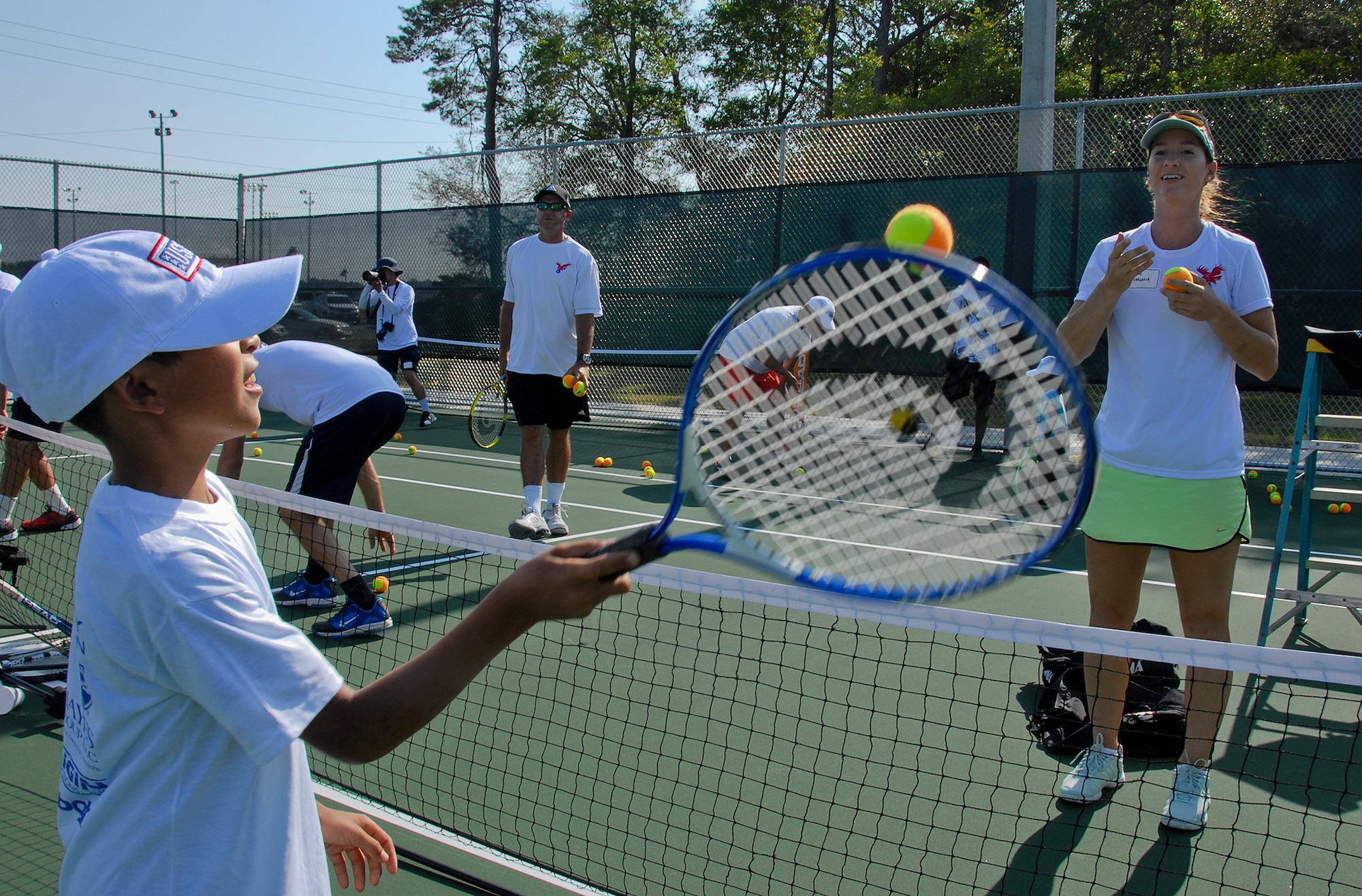 Adriana Solarova, a former professional tennis player, tosses a ball for a participant to return, at the grand opening of eight new tennis courts April 25 at Eglin Air Force Base, Fla.  The boy was one of 75 participants at the “Thanking Our Troops through Tennis,” or T3, event at the new courts, located next to Eglin’s consignment shop.  Free tennis clinics were offered by former tennis professional players, coaches and certified teaching professionals.  (U.S. Air Force photo/Kevin Gaddie)