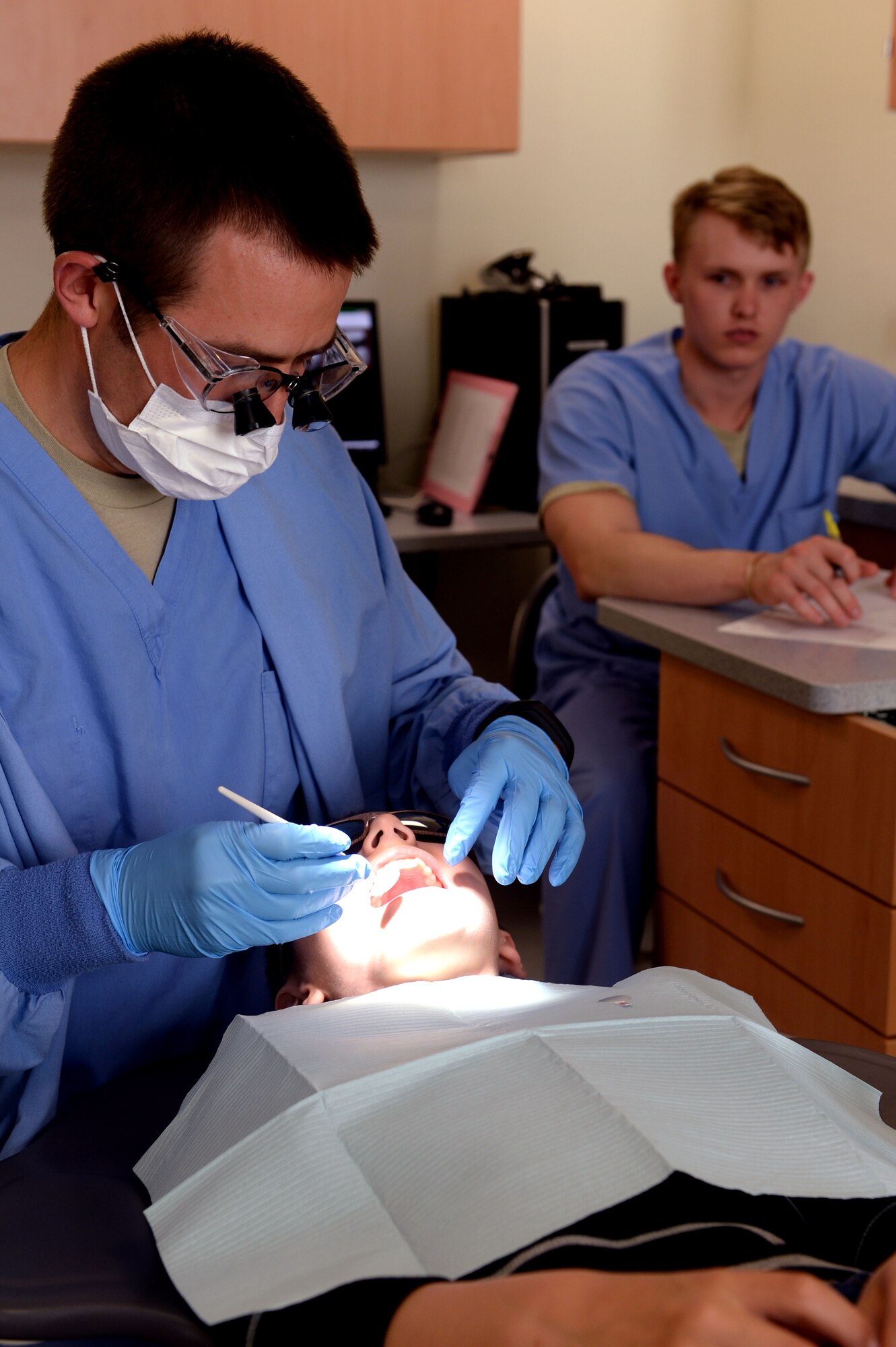 U.S. Air Force Capt. Mark Olsen, a 52nd Dental Squadron dentist, conducts an oral exam of Sean Jones, 9, while Airman 1st Class Evan Wolfe, 52nd DS dental assistant, annotates Olsen’s findings on Spangdahlem Air Base, Germany, April 23, 2014. While the clinic provides dental care to dependents as needed, most child patients are seen during kids’ clinics held twice a year. (U.S. Air Force photo by Senior Airman Alexis Siekert/Released)