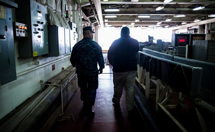 Petty Officer 3rd Class Wilson Araujo, Naval Health Clinic Charleston preventive medicine technician, talks with Samuel Hankins, a steward cook onboard USNS Zues (T-ARC-7), as they exit the interior of the ship Apr. 25, 2014, while the ship was in port Charleston, S.C. Araujo was conducting a shipboard sanitation inspection which is required for all USNS ships to dock internationally. (U.S. Air Force photo/ Airman 1st Class Clayton Cupit)