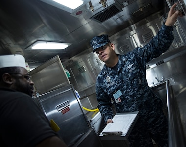 Petty Officer 3rd Class Wilson Araujo, Naval Health Clinic Charleston preventive medicine technician, talks with Samuel Hankins, a steward cook onboard USNS Zues (T-ARC-7),about sanitation standards Apr. 25, 2014, while the ship was in port Charleston, S.C. Araujo was conducting a shipboard sanitation inspection which is required for all USNS ships to dock internationally. (U.S. Air Force photo/ Airman 1st Class Clayton Cupit)