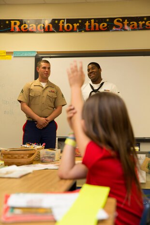 Regan G. Rodringuez, second grader of Harbordale Elementary School in Fort Lauderdale, Fla., raises her hand to ask a question to Cpl. Brandon M. Carteaux, native of Dallas, Ga., and amphibious assault crew chief with 2nd Assault Amphibian Battalion, 2nd Marine Division, Marine Corps Base Camp Lejeune, N.C., and a Airman Apprentice Daniel Goodridge, native of Brooklyn, N.Y., and aviation boatswains mate (fueling), during a school visit to Harbordale Elementary School in Fort Lauderdale, Fla., April 30, as part of a community relations event of Fleet Week Port Everglades 2014. Three Marines from 2nd AAV Bn., and 2nd Battalion, 6th Marine Regiment, 2nd Marine Division, as well as Sailors from the USS New York (LPD 21) and Carrier Strike Group 12 spoke to more than 450 Harbordale Elementary students about their experiences in the military and on ship. (U.S. Marine Corps photo by Sgt. Alicia R. Leaders/Released)