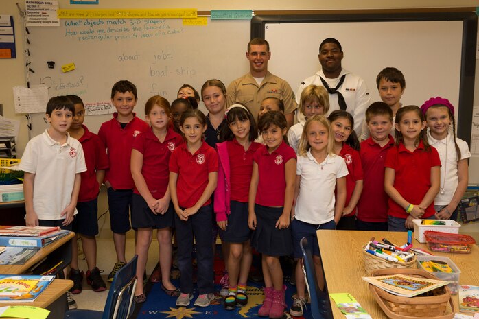 Second-grade students pose with Cpl. Brandon M. Carteaux, native of Dallas, Ga., and amphibious assault crew chief with 2nd Assault Amphibian Battalion, 2nd Marine Division, Marine Corps Base Camp Lejeune, N.C., and Airman Apprentice Daniel Goodridge, native of Brooklyn, N.Y., and aviation boatswains mate (fueling), during a school visit to Harbordale Elementary School in Fort Lauderdale, Fla., April 30, as part of a community relations event of Fleet Week Port Everglades 2014. Three Marines from 2nd AAV Bn., and 2nd Battalion, 6th Marine Regiment, 2nd Marine Division, as well as Sailors from the USS New York (LPD 21) and Carrier Strike Group 12 spoke to more than 450 Harbordale Elementary students about their experiences in the military and on ship. (U.S. Marine Corps photo by Sgt. Alicia R. Leaders/Released)