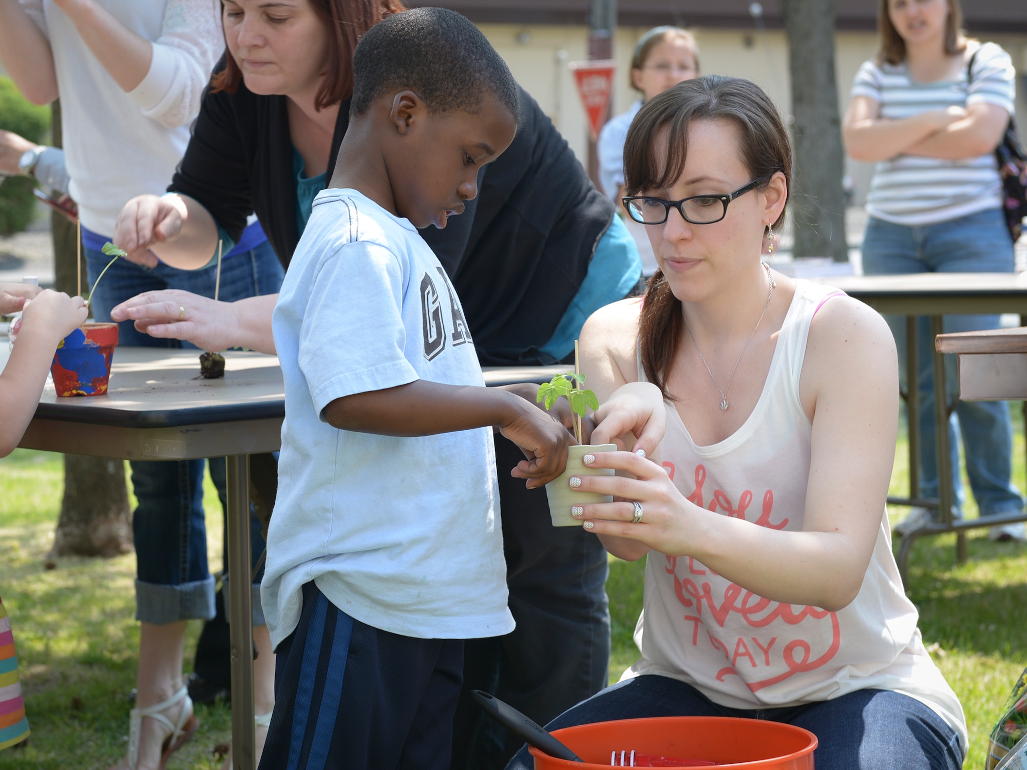 Angela Richards, local volunteer, plants marigold seedlings with children at Yokota Air Base, Japan, April 26, 2014. The volunteers reused several materials in the process to promote recycling during the Earth Week event. (U.S. Air Force photo by Airman 1st Class David Danford/Released)