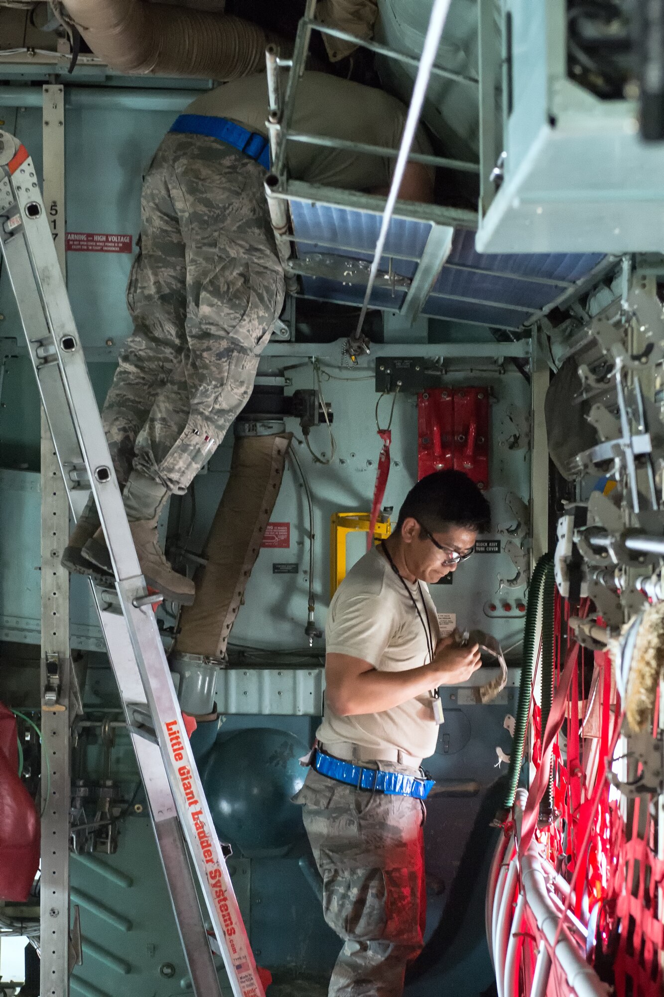 (Right to left) Airmen 1st Class Alexander Buenviaje and Nathan Judd, both from the 374th Aircraft Maintenance Squadron electrical and environmental shop, disassemble parts of a C-130 Hercules at Yokota Air Base, Japan, April 28, 2014. Yokota maintainers spend their time troubleshooting maintenance issues on the flightline and conducting daily maintenance on the aircraft. (U.S. Air Force photo by Osakabe Yasuo/Released)