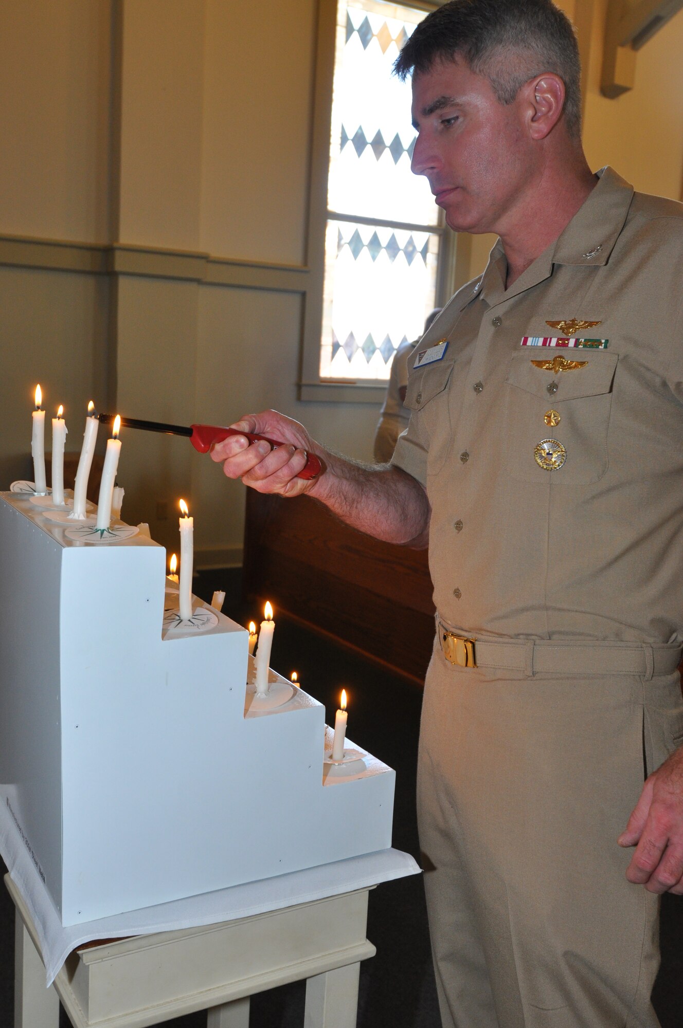 Navy Capt. Gil Miller, NAS Fort Worth JRB commander, joins in lighting a candle for the victims who have been afflicted by a criminal tragedy in today's 5th Annual Candlelight Vigil the Naval Air Station Fort Worth Joint Reserve Base, Texas. (U.S. Air Force photo/Master Sgt. Julie Briden-Garcia)