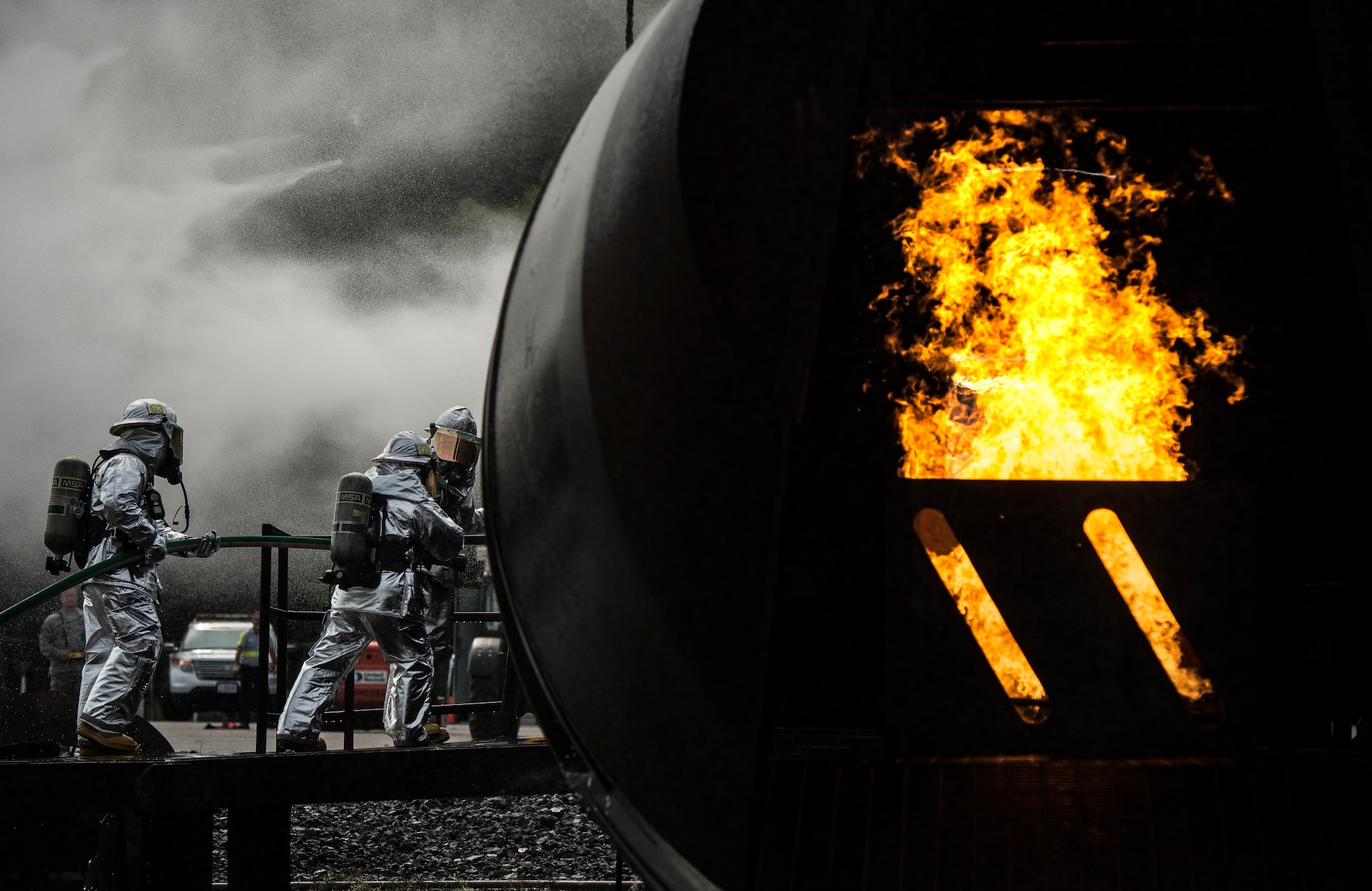 The 628th Air Base Wing leadership along with a trained 628th Civil Engineer Squadron fire fighter, prepare to breach a flaming aircraft simulator during a visit April 27, 2014, at the JB Charleston Fire Department. Col. Jeffrey DeVore, Joint Base Charleston commander, Capt. Timothy Sparks, JB Charleston deputy commander, Master Chief Petty Officer Joseph Gardner, Naval Support Activity command master chief, and Chief Master Sgt. Mark Bronson, 628th ABW command chief, visit units as part of a program designed to give base leaders a taste of what Airmen and Sailors do at their job centers every day. (U.S. Air Force photo/ Senior Airman Dennis Sloan)