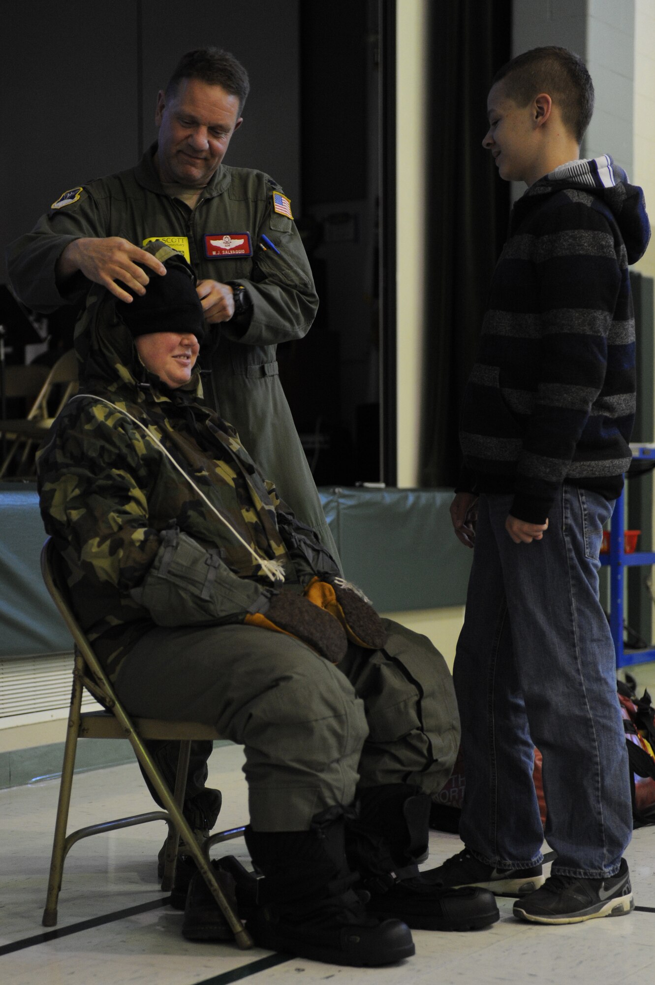 Lt. Col. William "Sal" Salvaggio, 109th Airlift Wing LC-130 instructor navigator, helps Kathryn Aitken, Scott Elementary School fifth grade teacher, don all of his cold weather gear during a presentation on April 22, 2014 at Scott Air Force Base, Ill. Salvaggio showed fourth and fifth graders what he does while he is in Antarctica, what gear he wears, what wildlife they see, and why they go. (U.S. Air Force photo by Senior Airman Sarah Hall-Kirchner/Released)