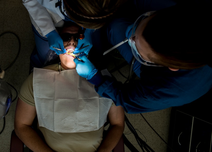 Lea Gillis, 628th Medical Group dental assistant (right), and Capt. Mary Sorrentino, 628th Aerospace Medicine Squadron general dentist (top), perform a routine dental examination on Airman 1st Class Craig Luce, 437th Ariel Port Squadron cargo processor Apr. 16, 2014, at the 628th Medical Group dental clinic on Joint Base Charleston – Air Base, S.C. Gillis makes sure that the operation runs smoothly and assists Sorrentino as she performs the dental procedures. (U.S. Air Force photo/ Airman 1st Class Clayton Cupit)