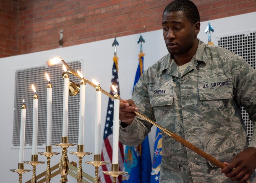 Senior Airman William Shelby, 90th Missile Wing Protocol, lights a Menorah during the Holocaust Remembrance event April 29 in the Fall Hall Community Center. (U.S. Air Force photo by Airman Malcolm Mayfield)
